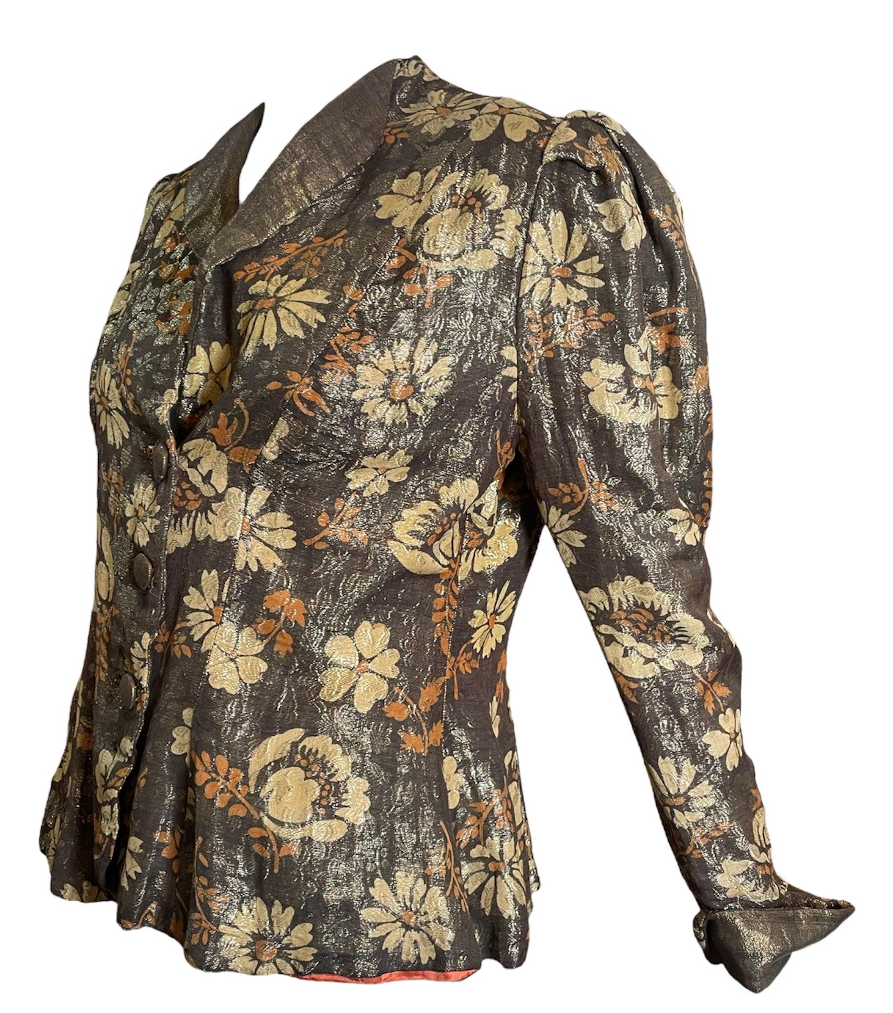 1930s evening jacket in luxurious gold lame. Shawl collared with fold over cuffs. Whimsical floral print. Fully lined with puffed shoulders.  Peplumed hem. Slight fraying at top button and very slightly around buttonholes. Unlabeled. Not visible