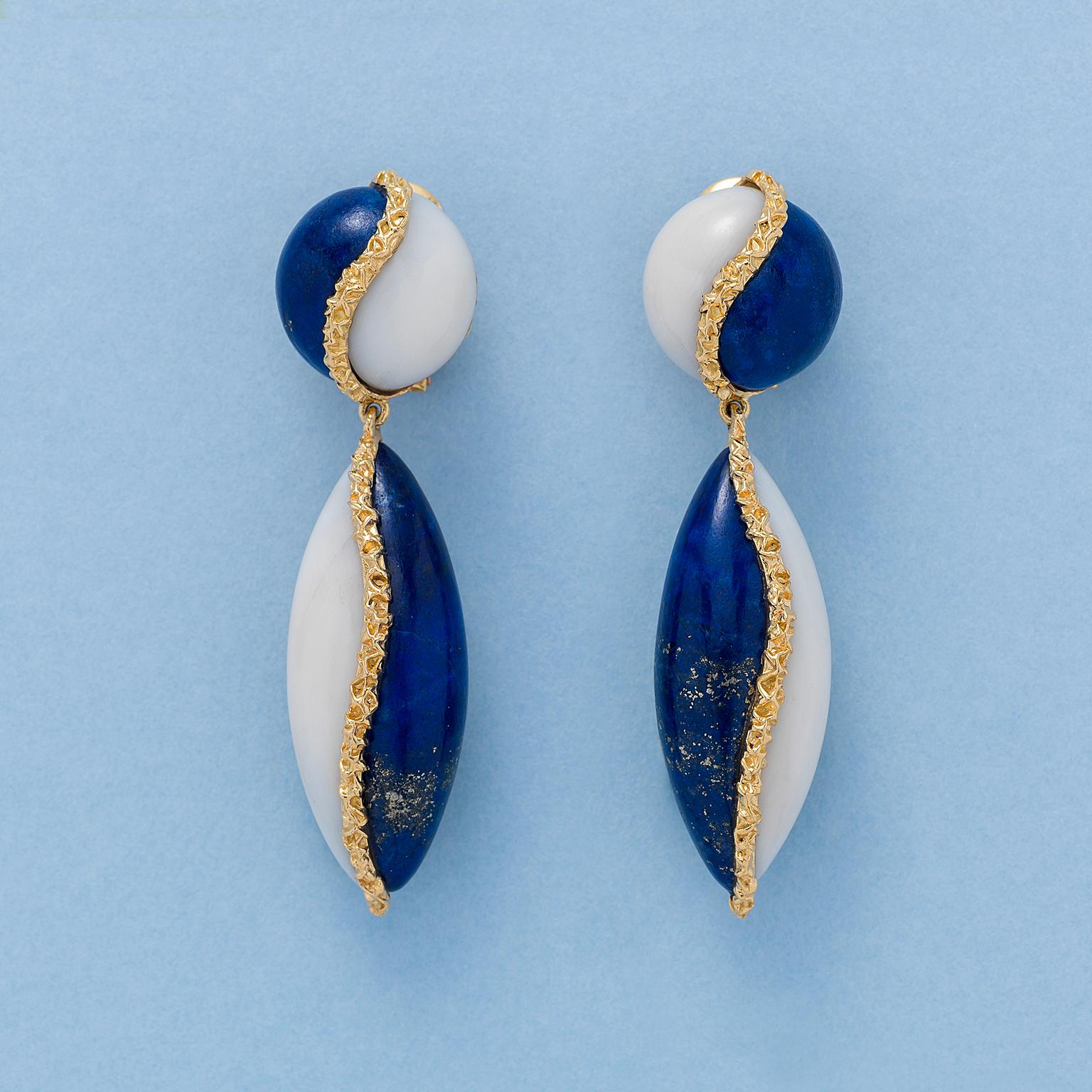 A pair of geometric, 18-carat gold, lapis, and white coral earrings, consisting of a round button and a navette shaped drop, each set with a cabochon cut slab of lapis and of white coral separated by an irregular, textured gold wire. France with