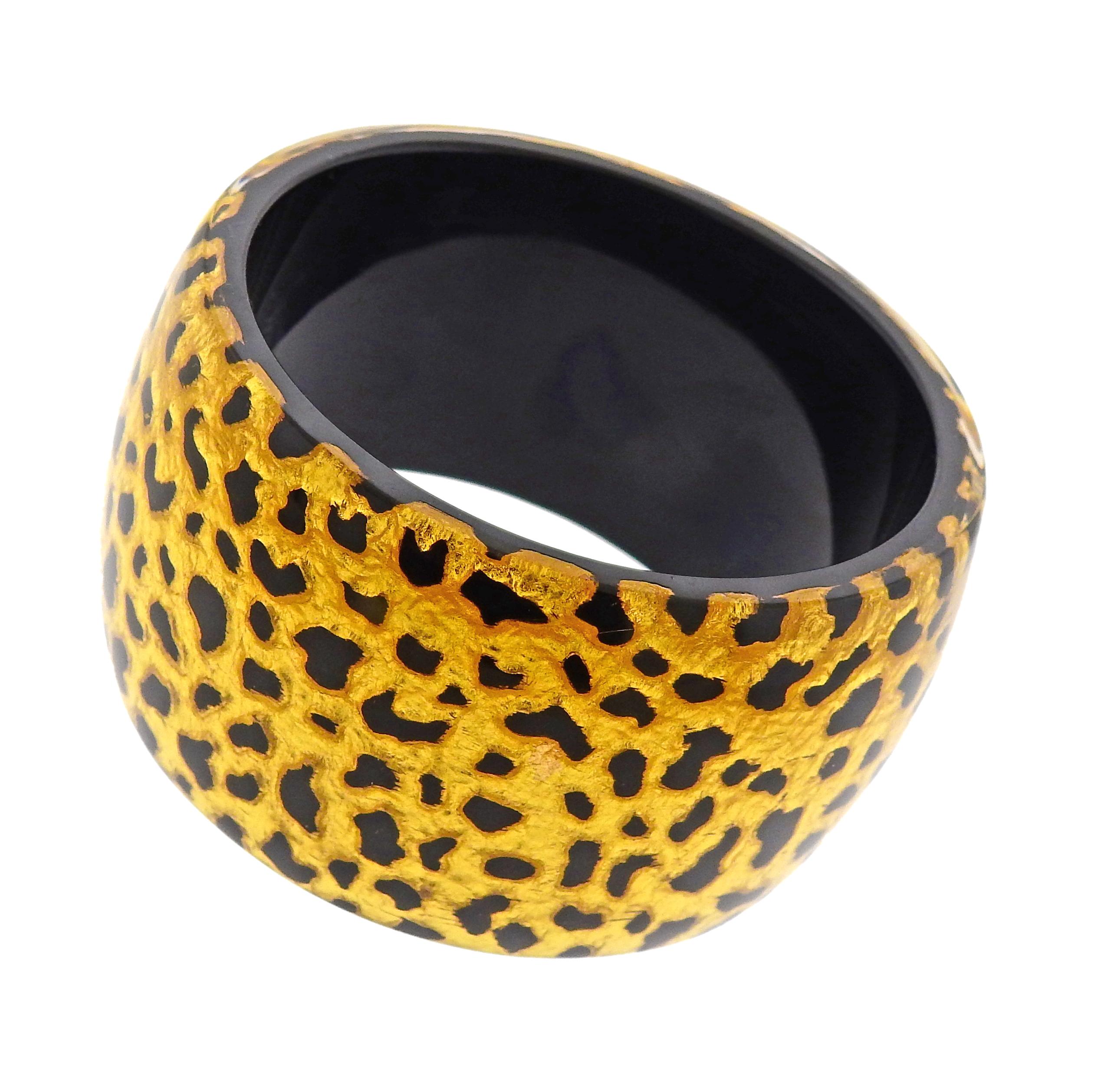 Pulsera brazalete ancha, engastada en baquelita con hojas de oro. La pulsera se ajusta a una muñeca de hasta 7