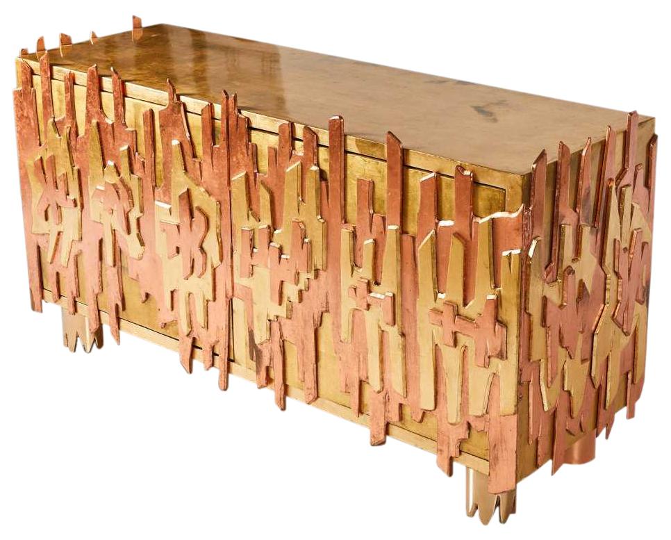 An incredible credenza by Pedro Baez of Mexico City. A rectilinear, gold-leaf, double-door, wood cabinet adorned on three sides with layers of two-tone-gold-leaf, abstract metal forms breaking the plane above and below. Resting on substantial,