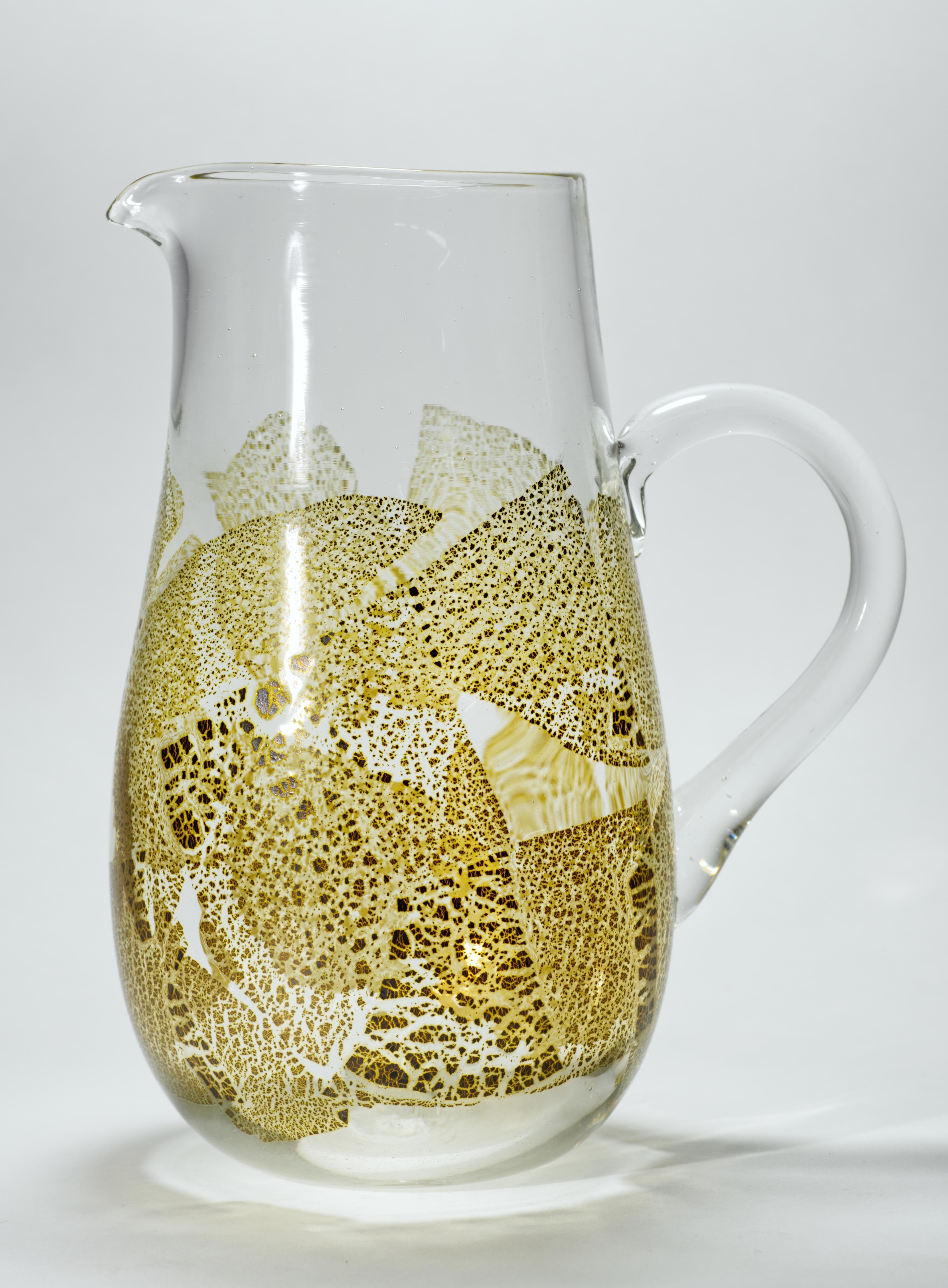 Krug aus Vintage-Glas mit abstraktem Golddekor auf klarem Glas; die Platzierung des Blattgoldes hebt die weichen, organischen Kurven des Kruges hervor.

Der Krug ist auf der Unterseite vom Künstler signiert und datiert. Die Signatur ist zwar schwer