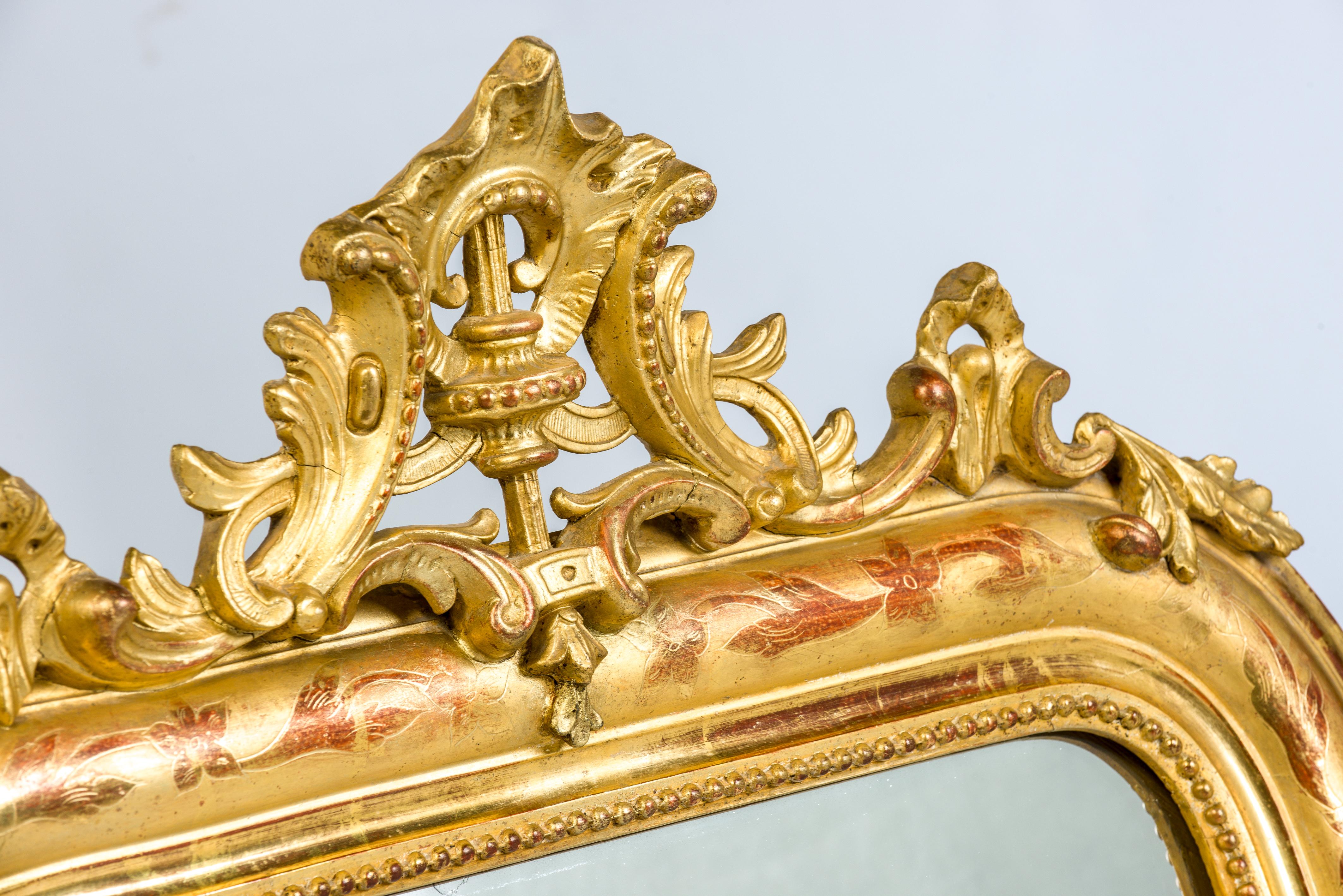 This beautiful gold leaf gilded Louis Philippe mirror has an ornate crest on top.
The upper corners are curved, as is typical for Louis Philippe.
Both frame and crest are gold leaf gilt. The red 'bole' shines through the gold giving the gold it's
