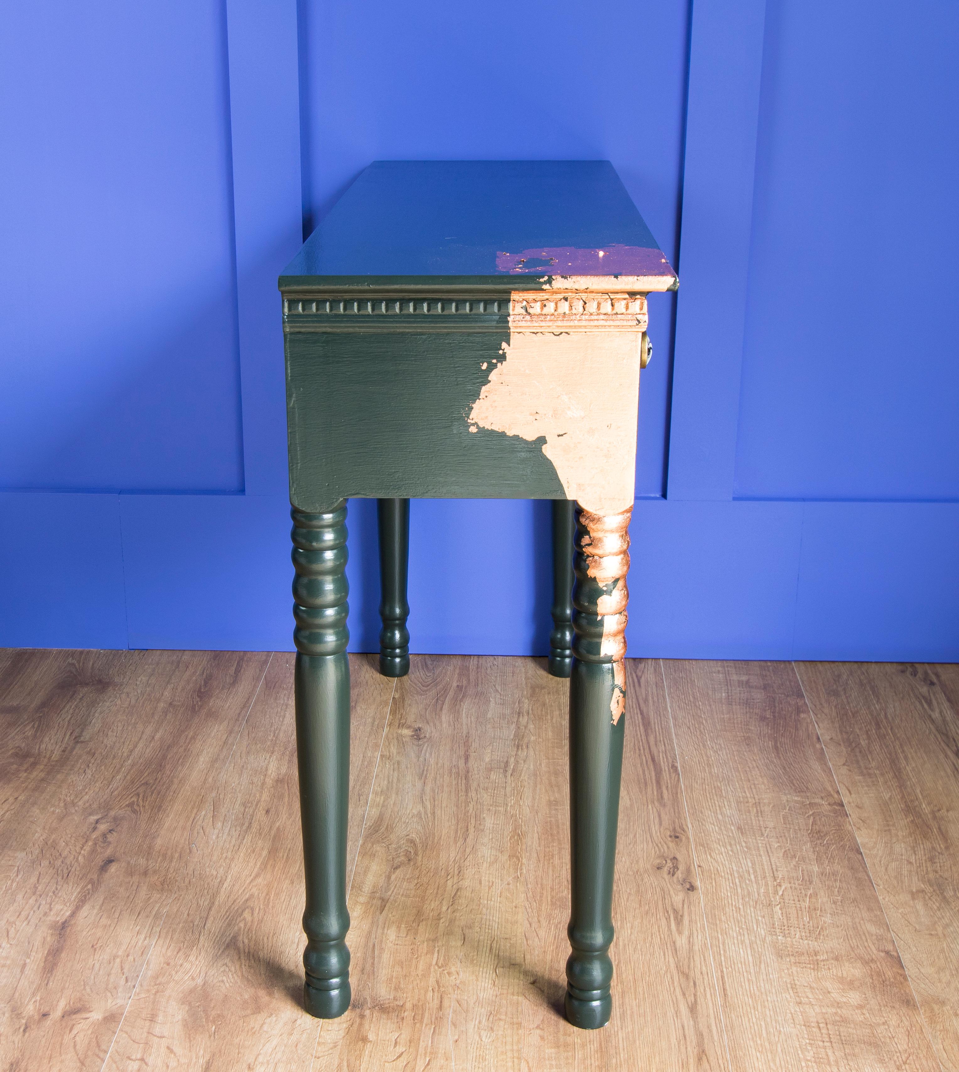 This little but sturdy vintage console table has been hand painted in Farrow & Ball 'Studio Green' paint and has Rose Gold Leaf work to one corner and leg. Two new legs were turned to restore this vintage table for a second life! There is a satin