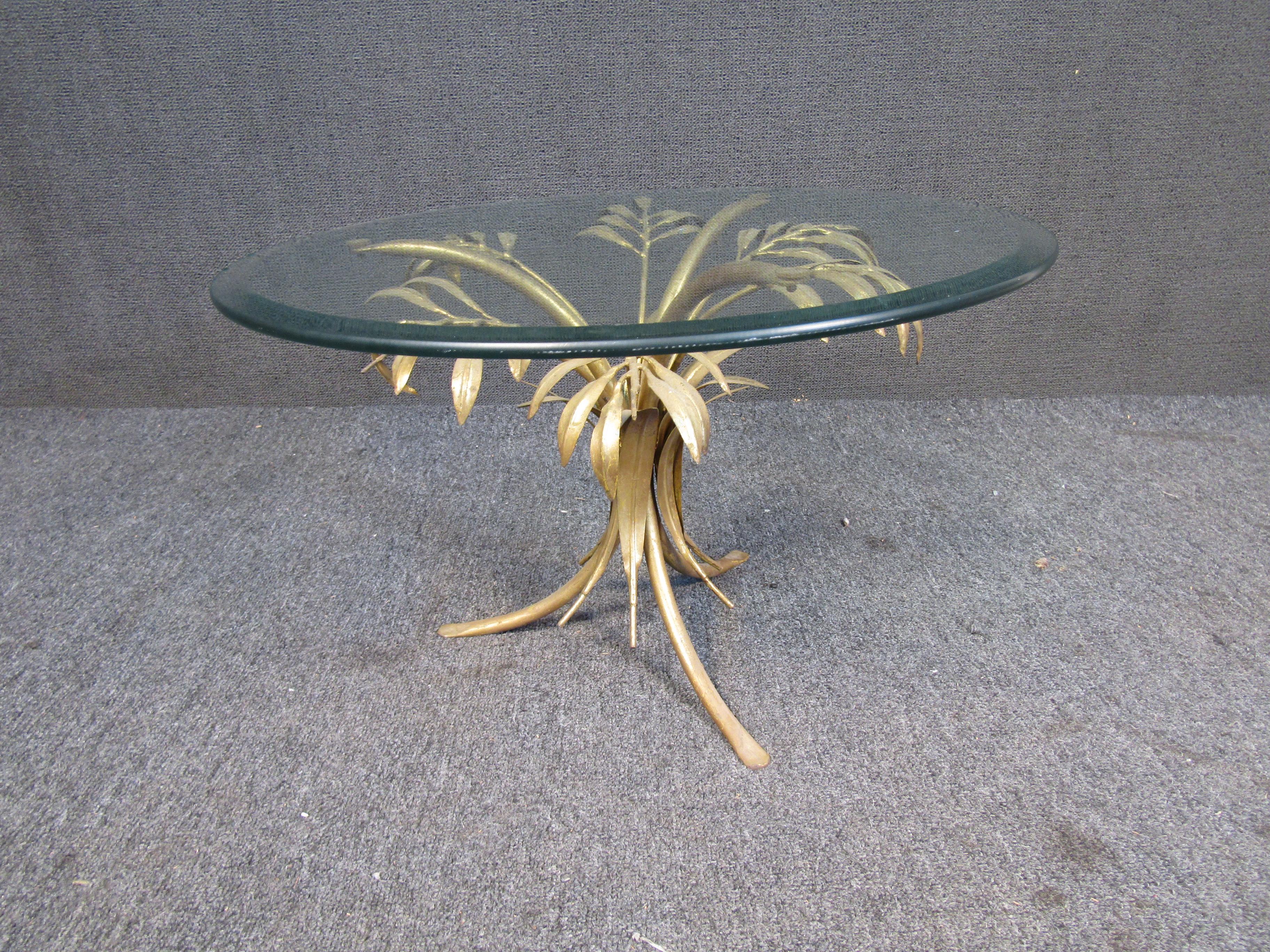 With intricate gold leaf palm tree-themed designs as its stand, this unique side table features a large rounded top of thick glass. Please confirm item location with seller (NY/NJ).