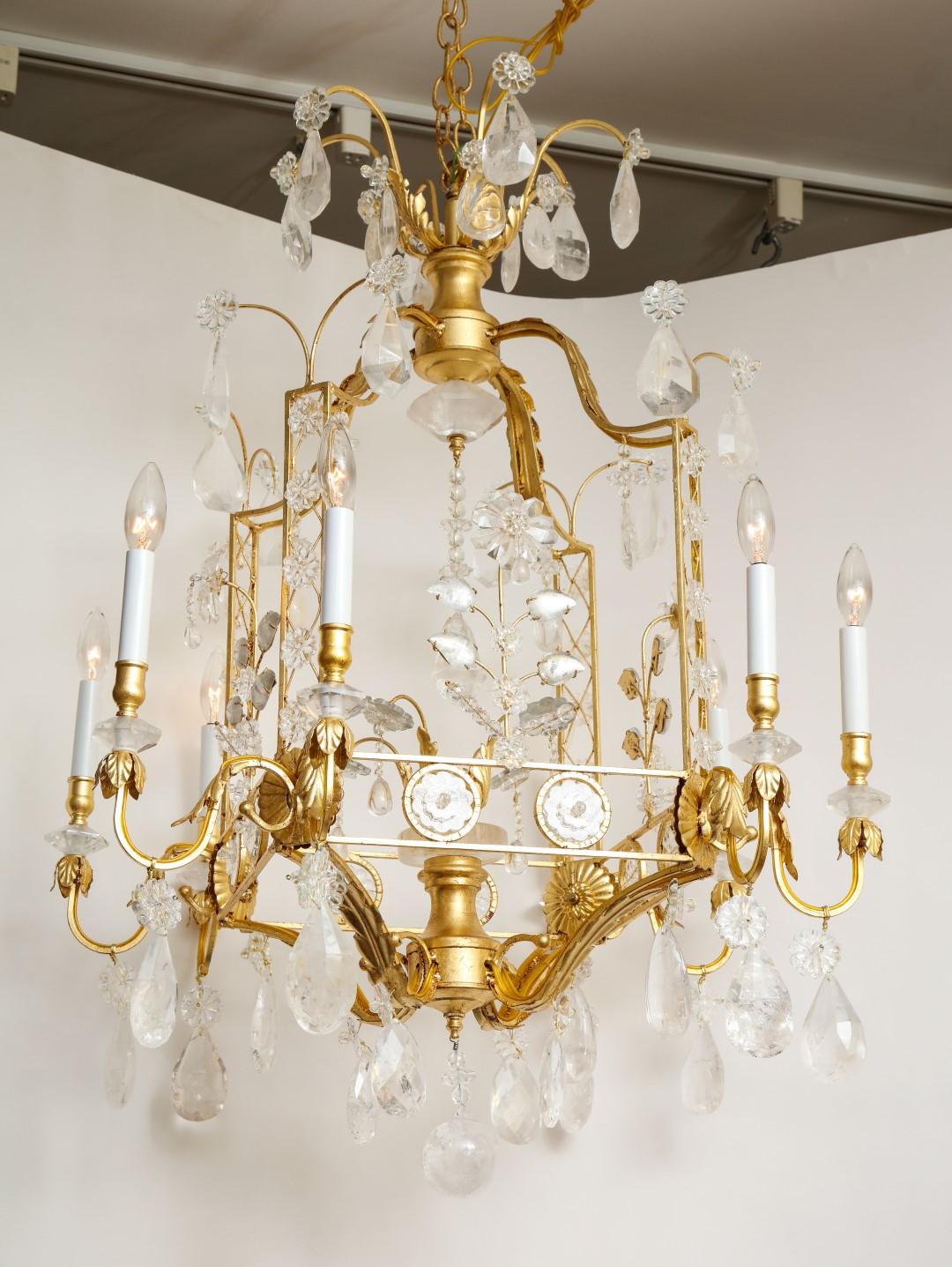 A new, eight light Louis XVI-style cage form chandelier with a yellow gold gilt metal finish. The square arched frame with squared corners, having lattice pattern vertical elements with rock crystal rosettes. Each corner issuing two candle arms with