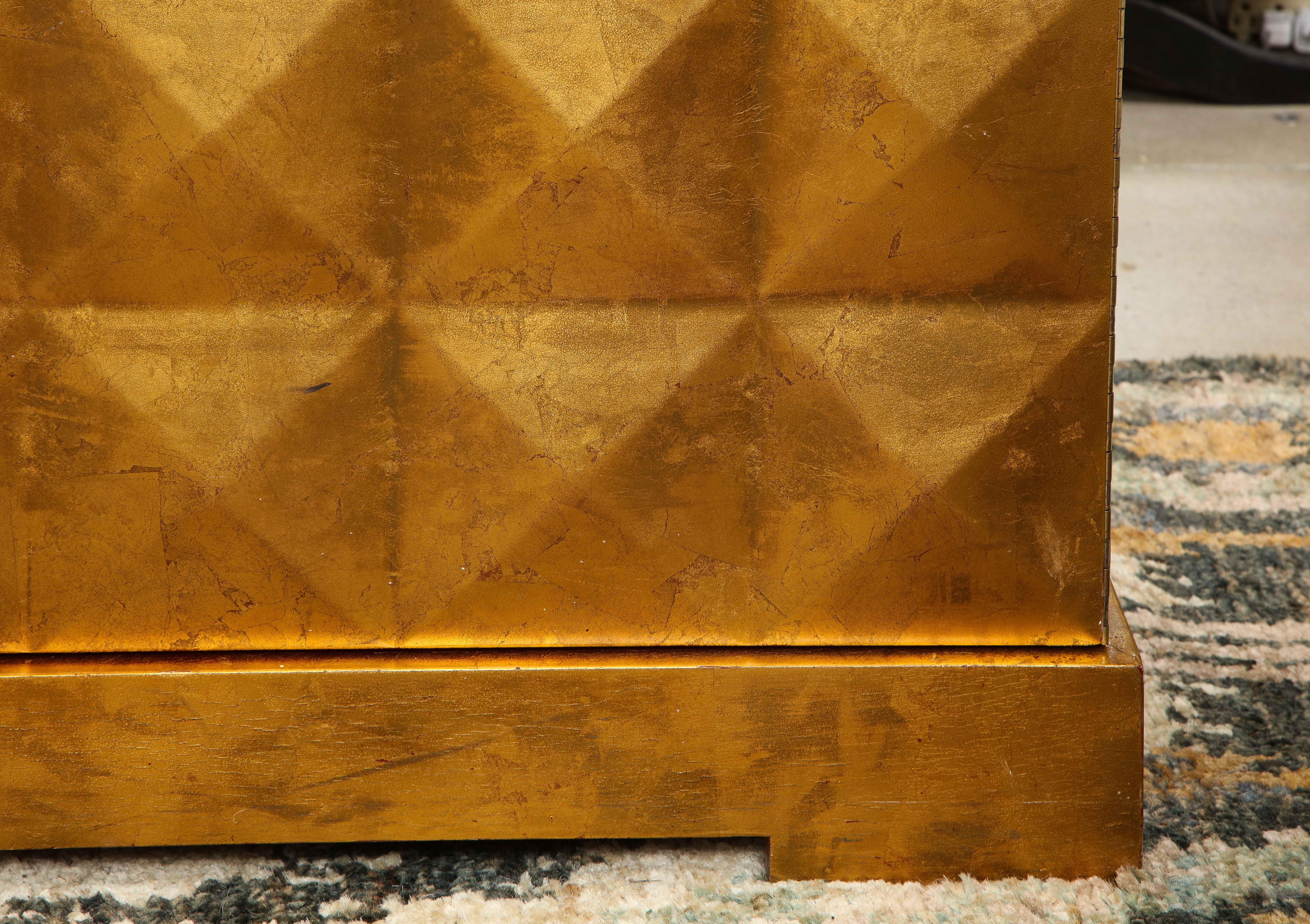 A stunning gold leaf two door cabinet with pyramid studs sits on slightly raised feet. Possibly Baker.