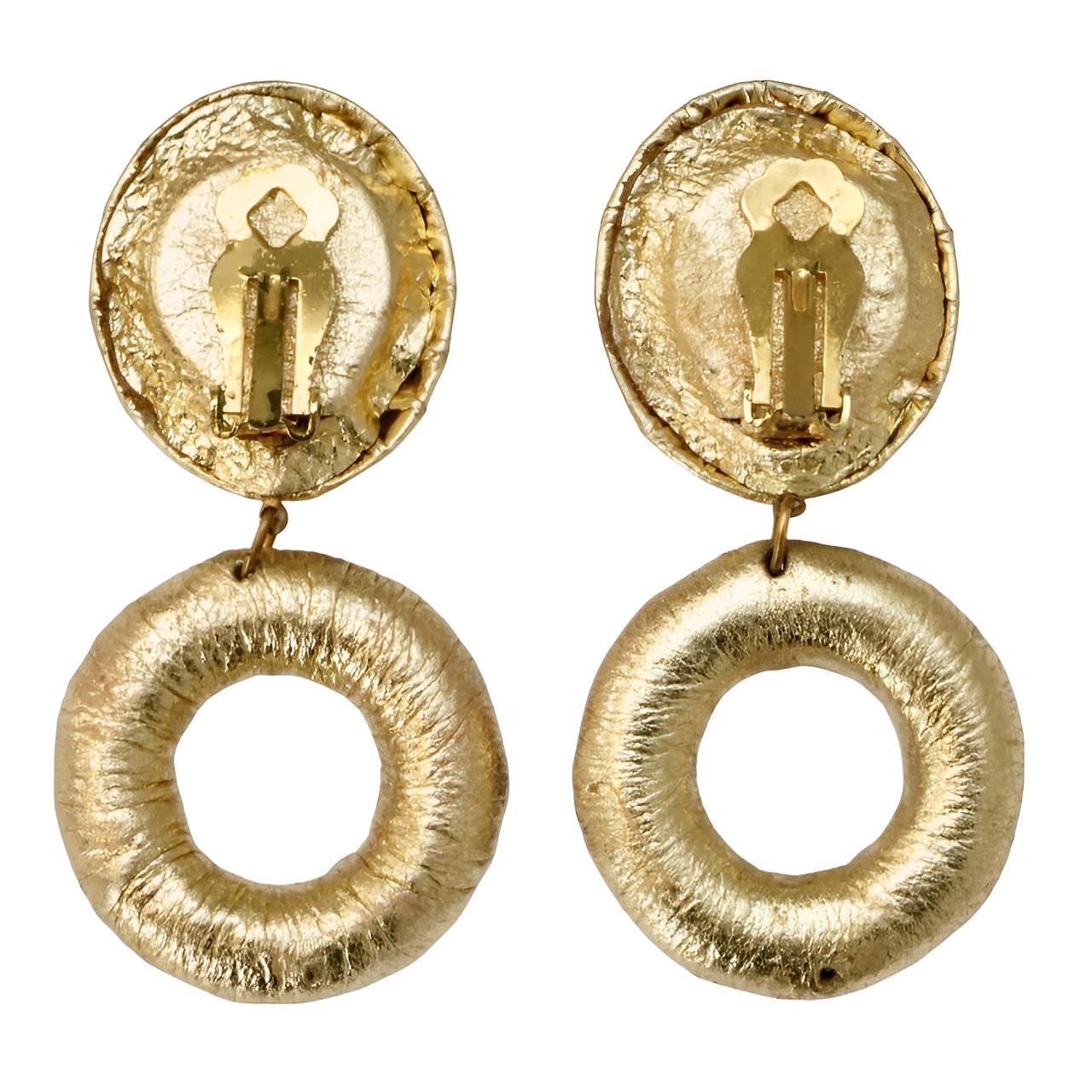 Fabelhafte goldene Leder-Clip-Ohrringe mit mehrfarbigen Strasssteinen aus Glas für den Ring und einem magentafarbenen, smaragdgrünen Strassstein für die Spitze.

Die Länge beträgt 7,2 cm / 2,8 Zoll, der Durchmesser der Reifen beträgt 3,4 cm / 1,3