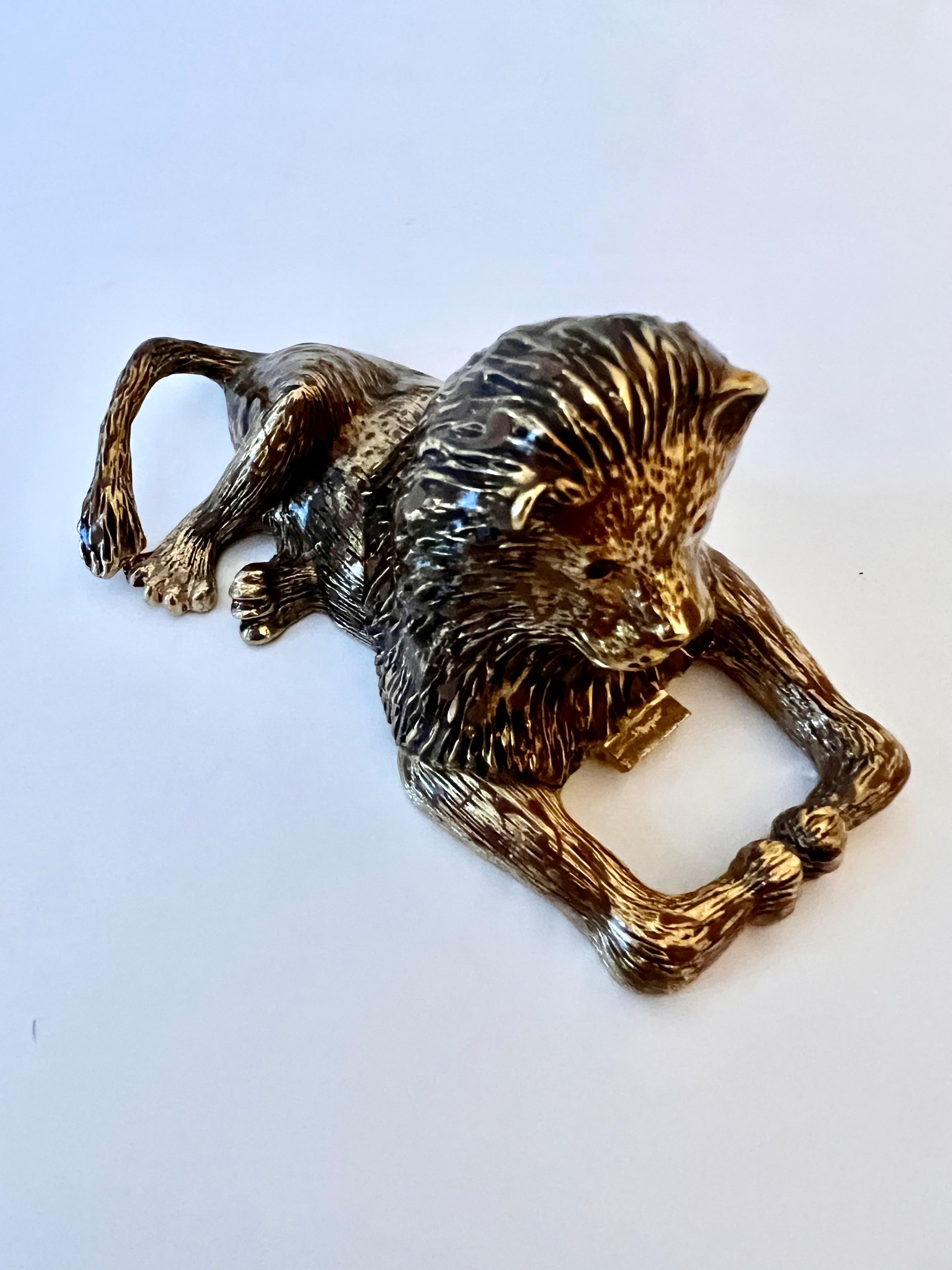 A gilt lion bottle opener ready for the kitchen or bar.   The reclining piece is perfect for the bar aficionado or with a bar with a theme.  The eyes are a topaz style stone.  a compliment to many bars