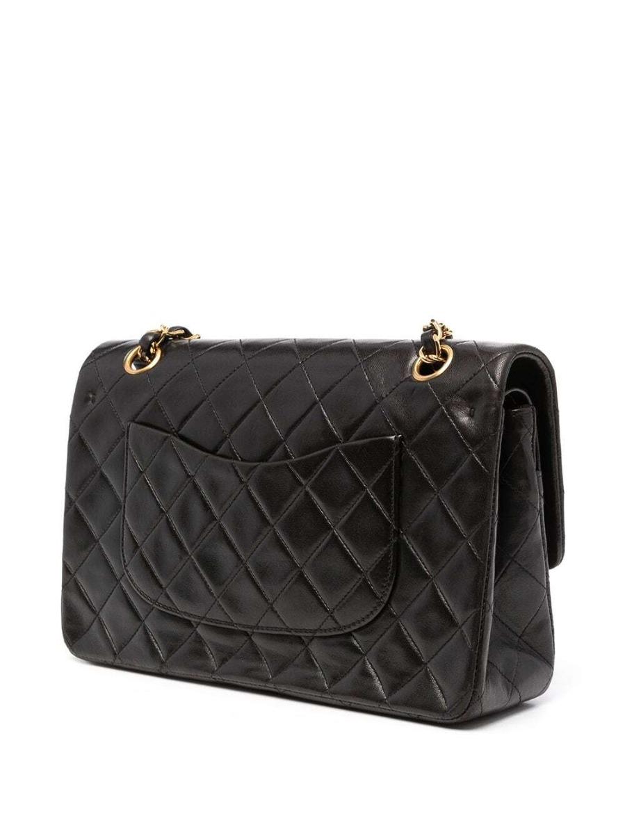 This iconic Chanel 10 inch bag is crafted from quilted black lambskin and features a double flap. On the front flap there is the classic CC logo twist lock and on the second flap a stud closure with one slip-in pocket. The inside lining is covered