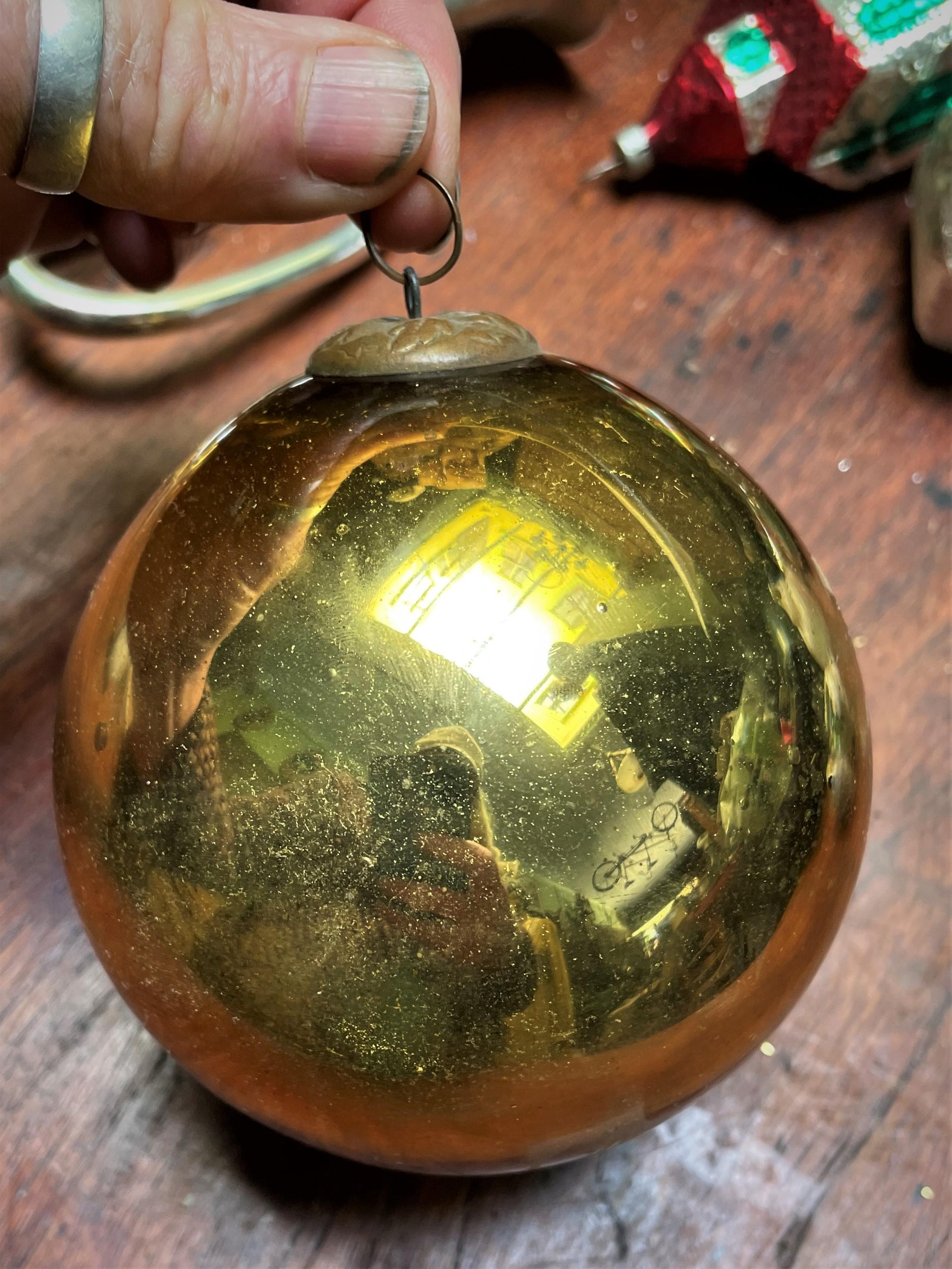 This is a great example of a gold mercury glass German Kugel. Kugels (which means balls in German) originated from witch balls that were glass balls that, in the 17th century, were hung in doorways and windows to ward of witches who were thought to