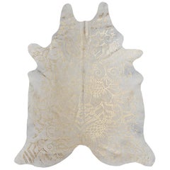 Alfombra de piel de vaca color crema con estampado Boho Batik metalizado dorado, mediana