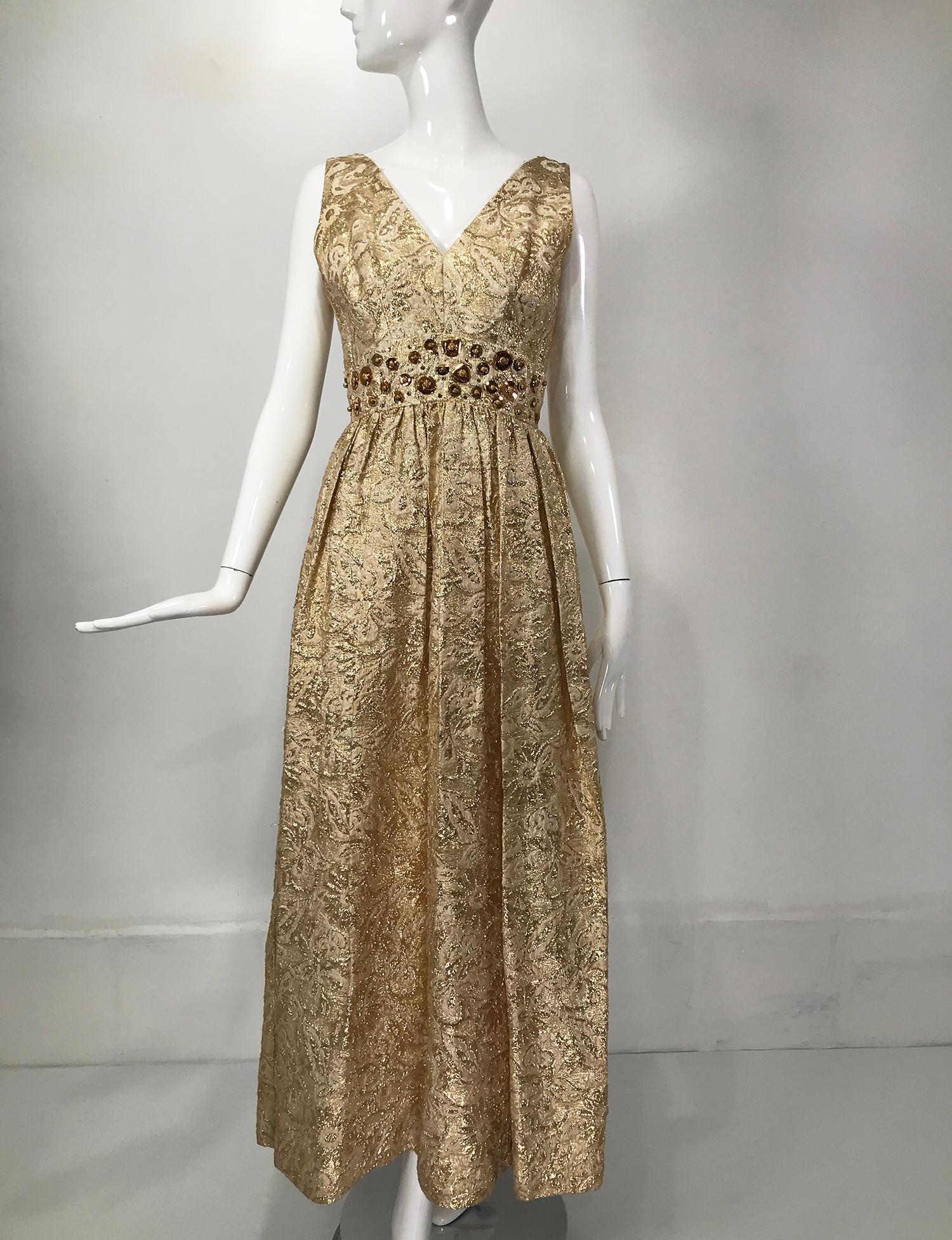 Gold metallic brocade V neck empire maxi dress from the 1970s. Sleeveless dress has a V neckline, an empire waist is sewn with large gold sequins and beads, the skirt is lightly gathered below the bust and falls full to the hem. The dress is lined,