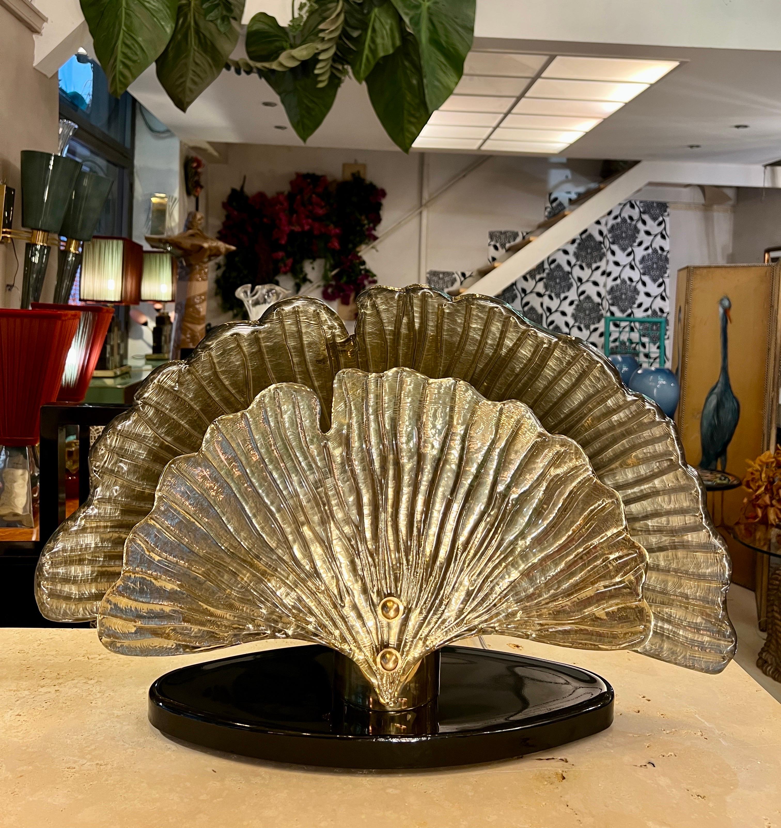 Lampada da tavolo in vetro di Murano specchiato oro con foglie di Ginkgo, anni '80.
La lampada è composta da due foglie di Ginkgo in vetro di Murano color oro (una più piccola sul davanti e una più grande sul retro), un vetro di Murano nero ovale e