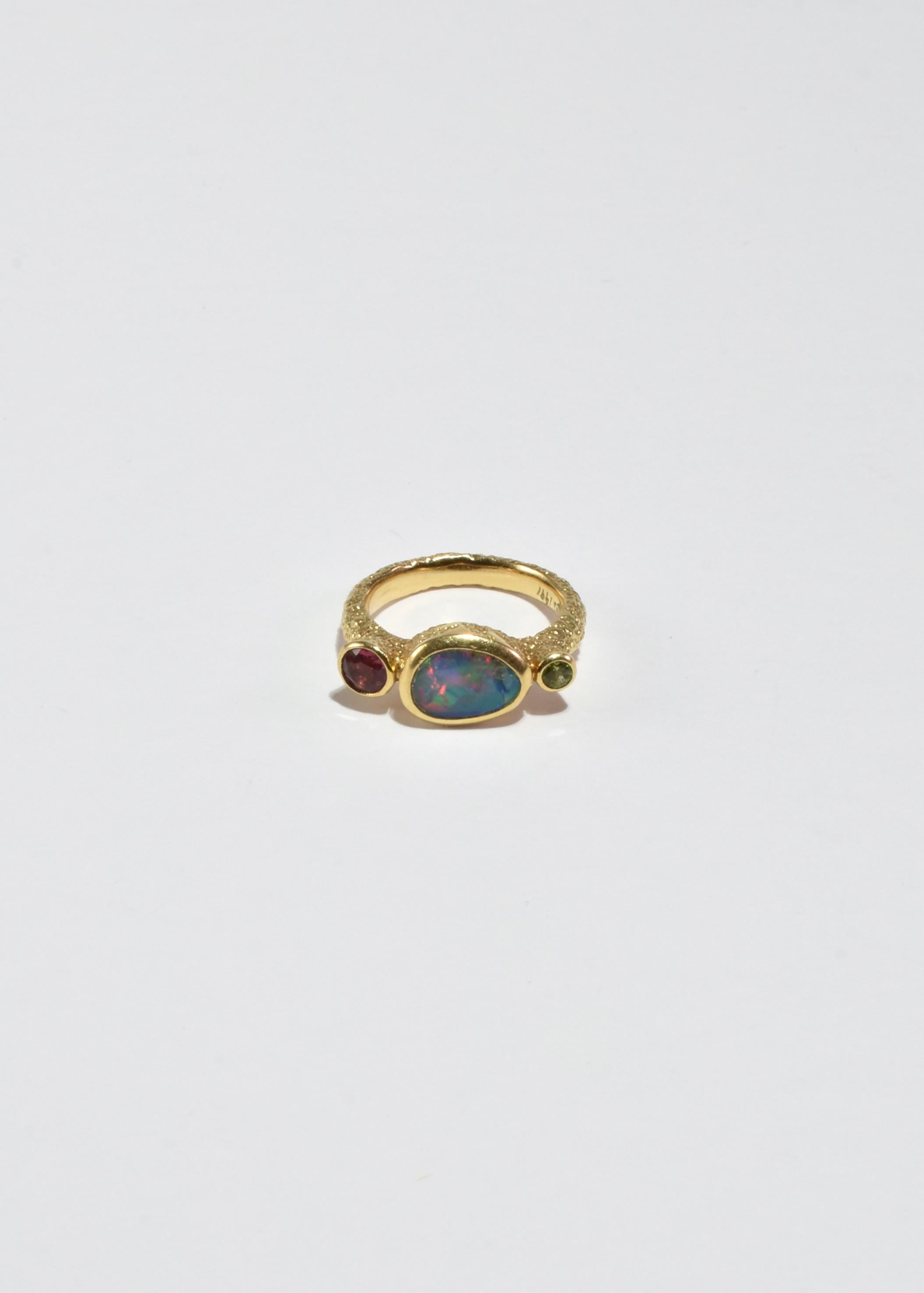 Stunning vintage hand-crafted gold ring with texture detail and opal, peridot, and ruby stones. Signed 18k, 1991.

Material: 18k gold, opal, peridot, ruby.