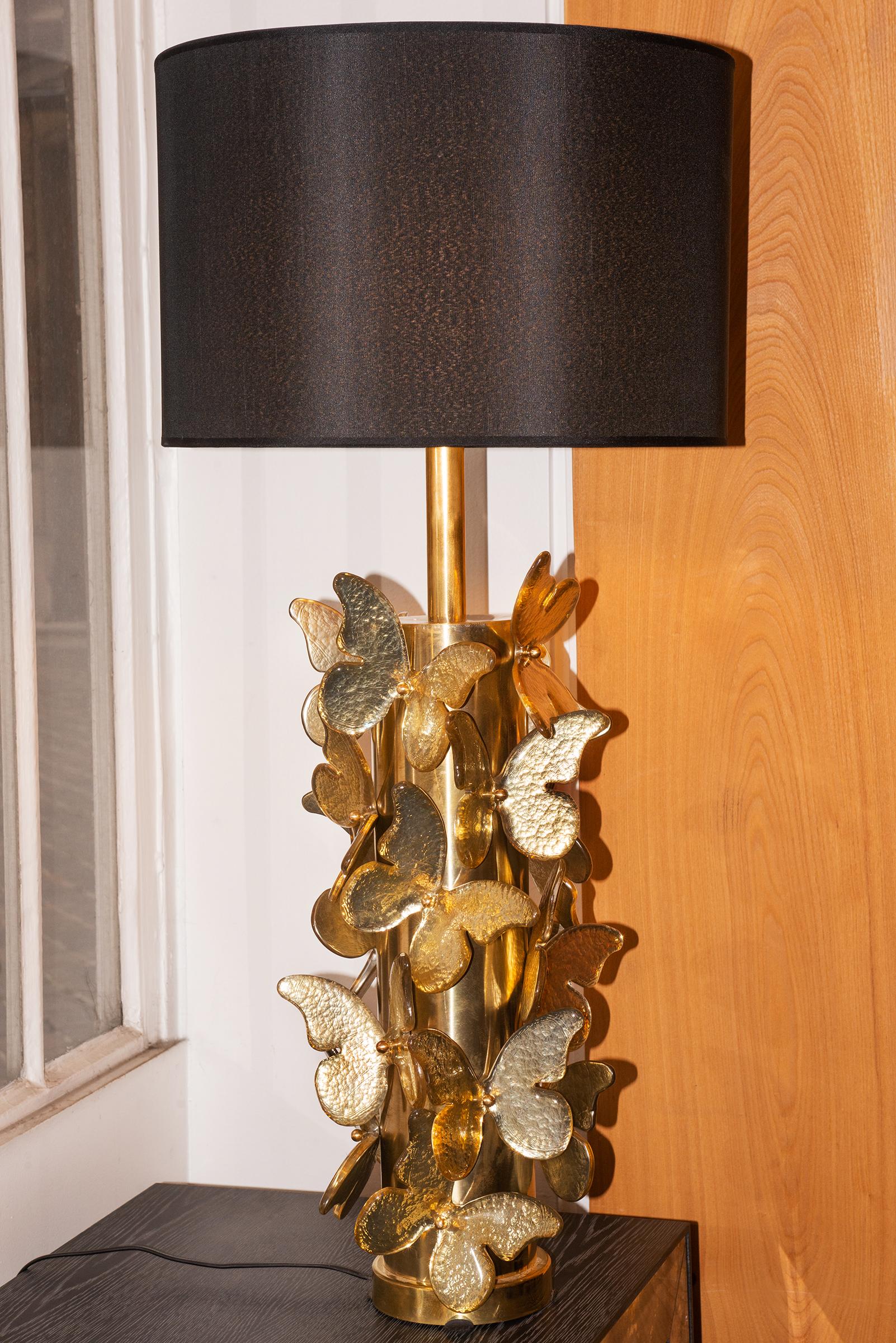 Table Lamp Gold Murano Butterflies with polished
brushed brass base table lamp ornamented with murano
glass butterflies with gold leaf taken under the murano glass.
With black lamp shade included: Diameter 43cm.
Table lamp base: Diameter 27cm,
