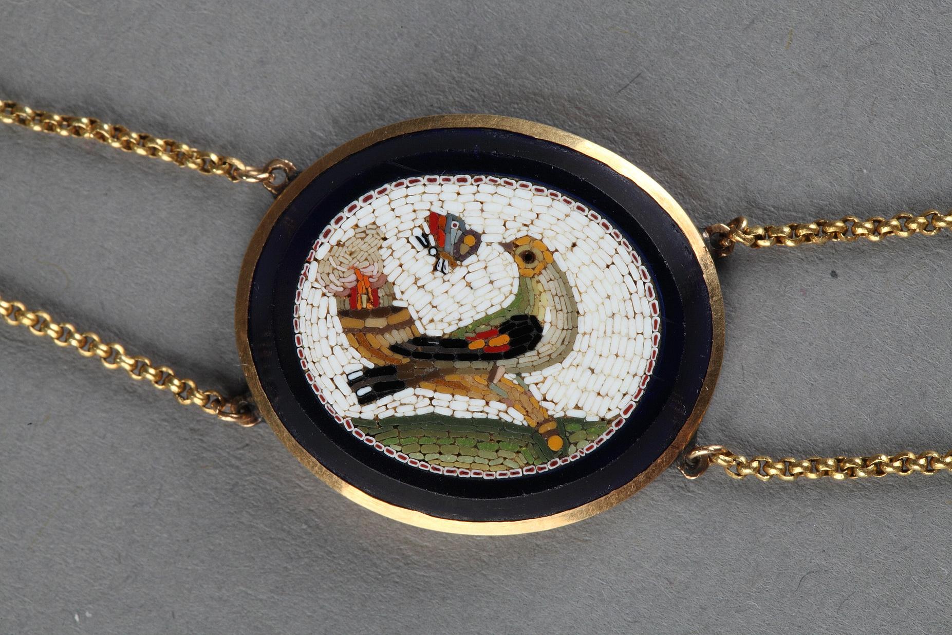 A gold necklace and micromosaic. The necklace is composed of seven micromosaic medallions set in dark blue glass. Two gold strands support the micromosaics between them. The subjects of the micromosaic plates are uncommon, as they do not represent