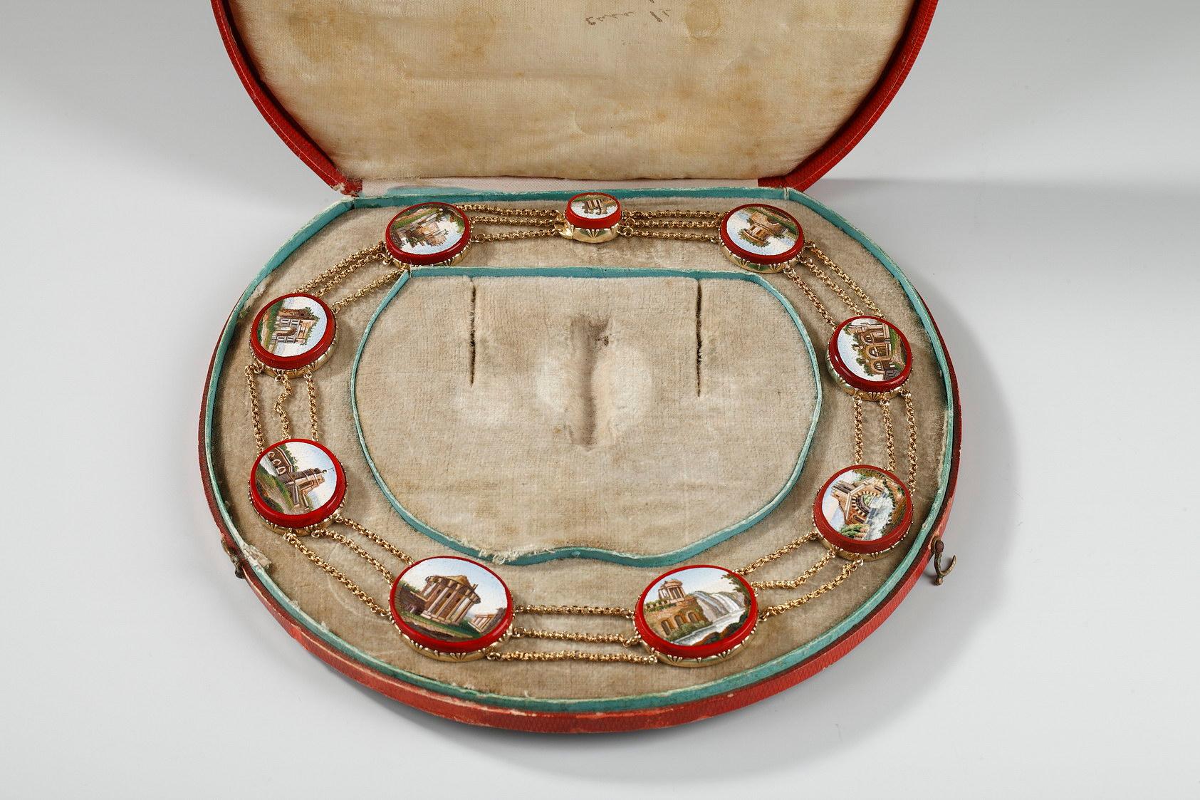 Un collier en or à trois brins présente neuf micromosaïques ovales enchâssées dans des ovales de verre purpurin rouge et reliées par des chaînes en or à trois festons. Chaque micromosaïque représente un monument de la Rome antique.
les