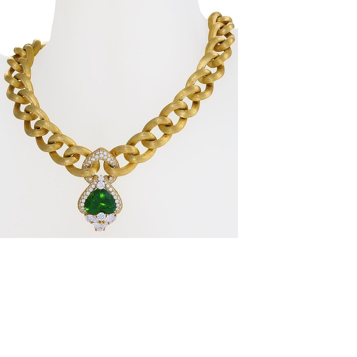 An 18 karat gold necklace with peridot and diamonds by Henry Dunay. The necklace has brushed gold curb links centering one heart shape peridot with an approximate total weight of 15.60 carats; 6 round brilliant-cut diamonds and 4 marquise-cut