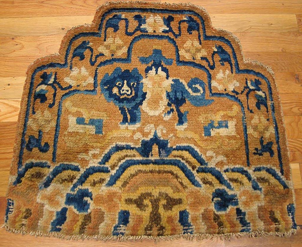 Small rugs with scalloped tops were woven to fit the backs of hardwood chairs and they were as Ningxia specialty. Often gold, as here, they employed familiar motives such as the lion dog above mountains and waves. This charming circa 1910 rug is in