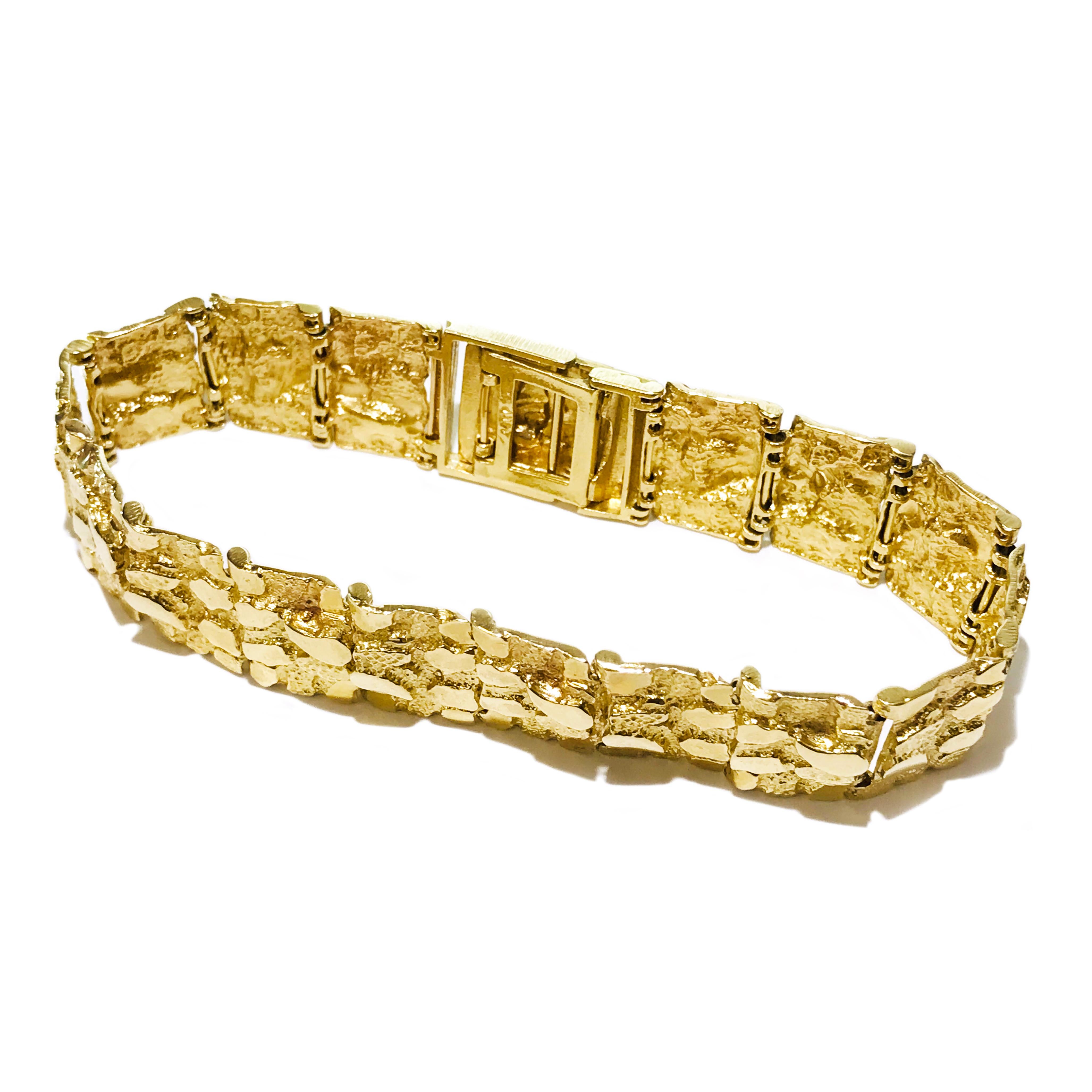 This 14K Gold Nugget Pattern Bracelet features a bold, retro-inspired design composed of sixteen textured nugget links. Measuring 18mm in width and 8.5 inches in length, it offers a substantial, luxurious feel on the wrist. The inside of the clasp