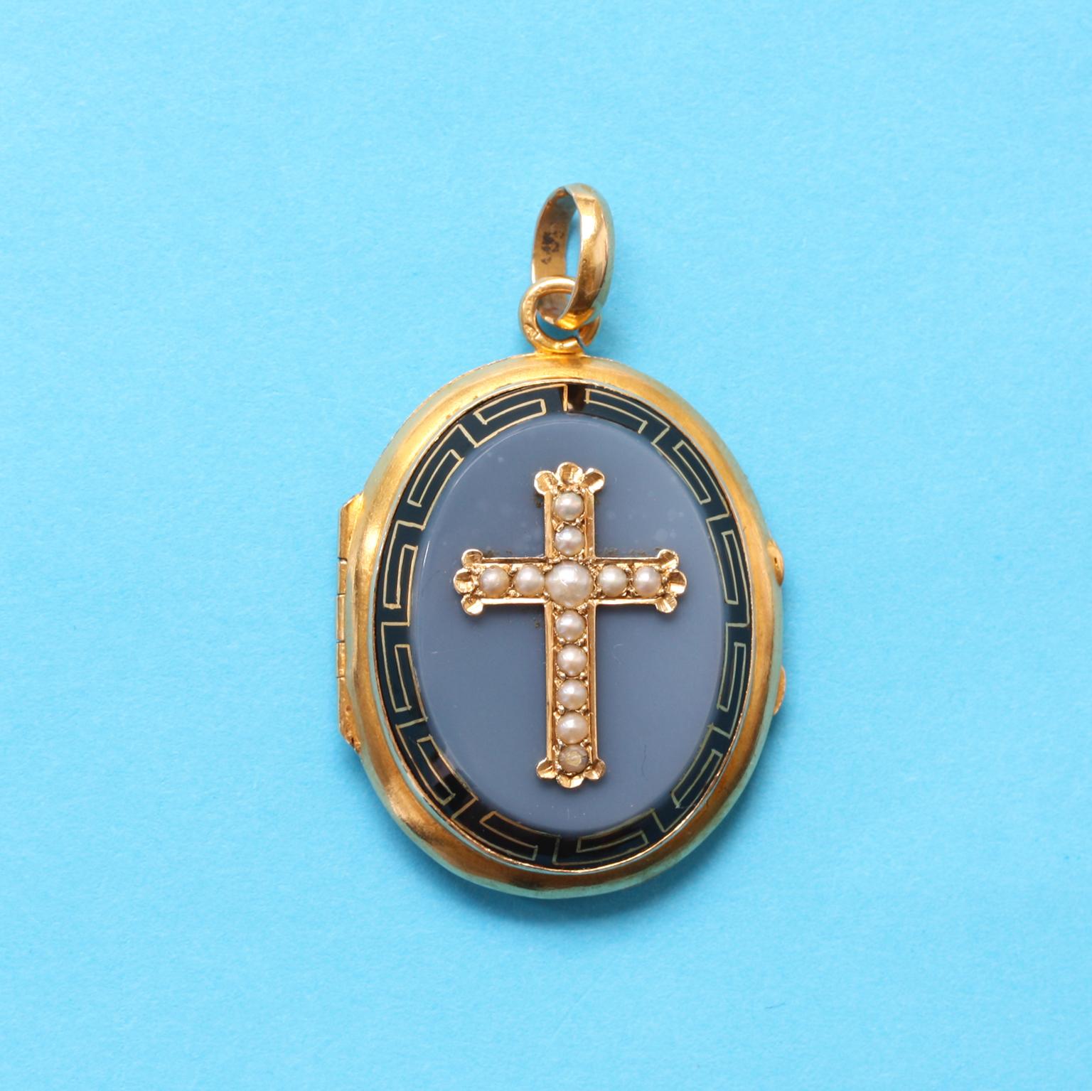 An 18 carat yellow gold oval locket with a pearl cross incrusted in an onyx plaque with a border of a black enamel meander border, with one glassed and hinged compartment, France circa 1890.

weight: 13.56 grams
dimensions: 4.5 x 2.7 cm
