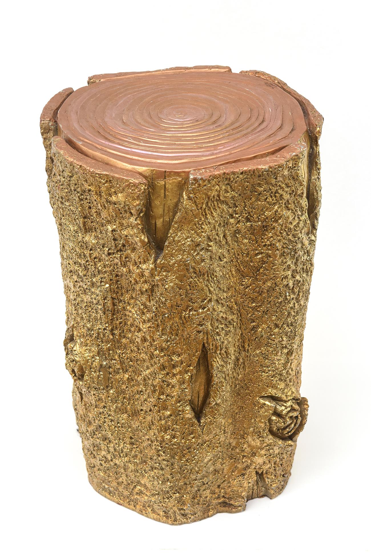 This unusual mixed media composition tree stump gold, small bench, foot stool, side table and or sculpture or art is an eye catcher in a room setting. It is composed of gold paint with an iridescent look on the top mixed in with some pink hues that