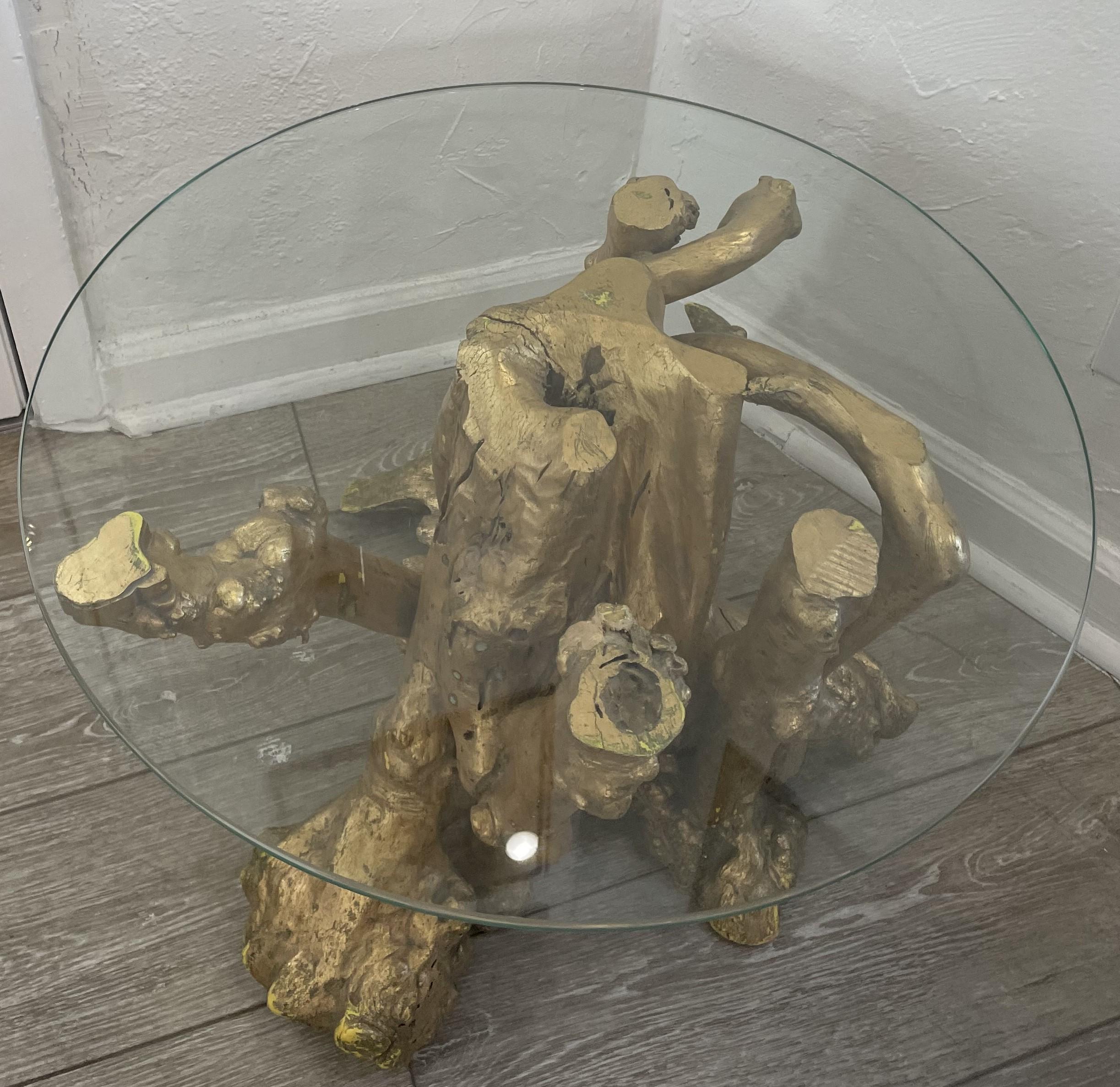 La base en racine naturelle de cette table, qui est finie en or, se distingue à la fois par sa beauté organique et son éclat. Le plateau en verre transparent permet une visibilité sous tous les angles. 
