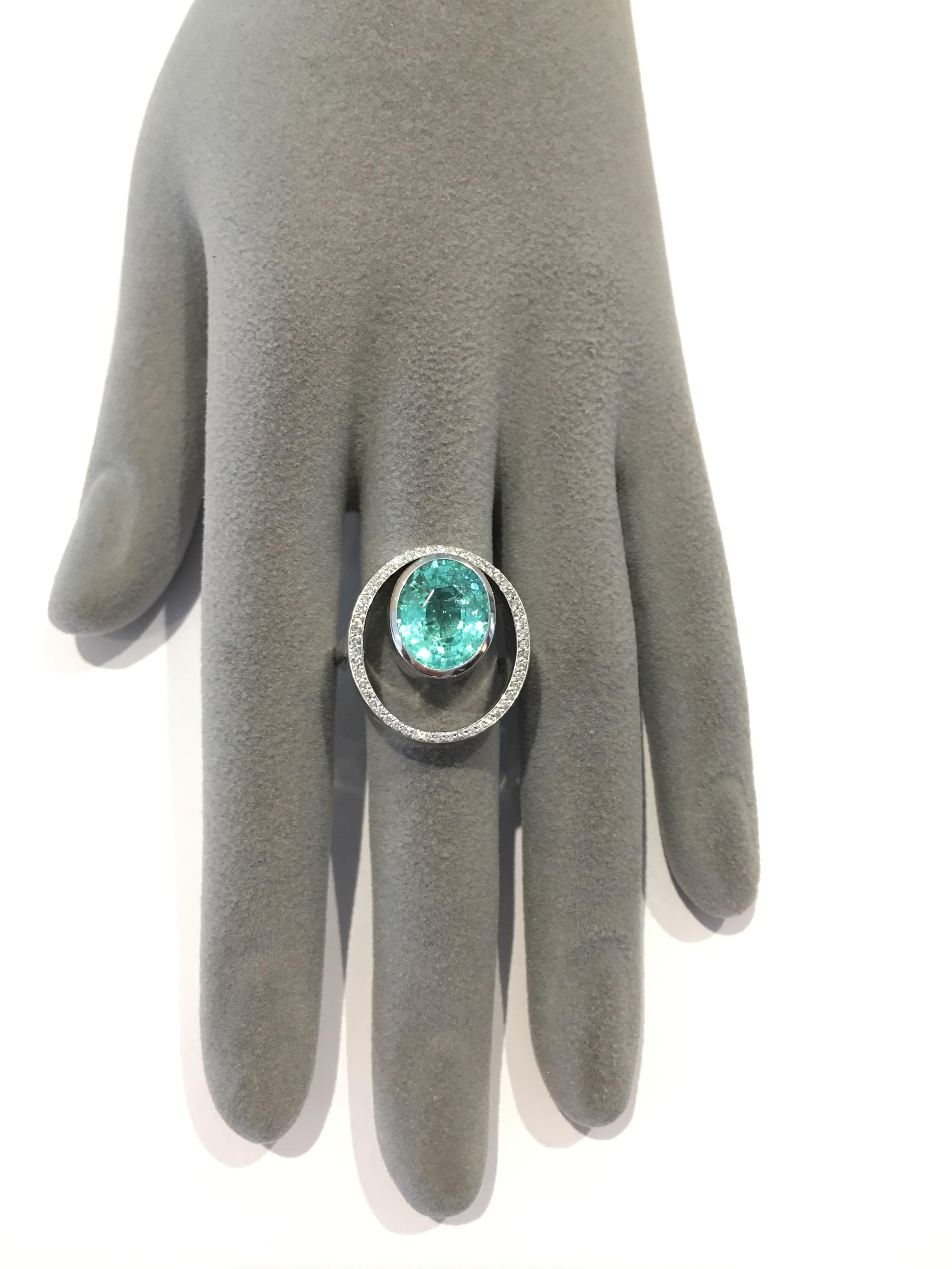 A Paraiba Tourmaline Peacock ring surrounded by pave set diamonds. The Mozambique oval cut gemstone has an intense aqua colour and it gives the illusion that it is floating inside the diamond set oval. The gemstone has natural inclusions.

Paraiba