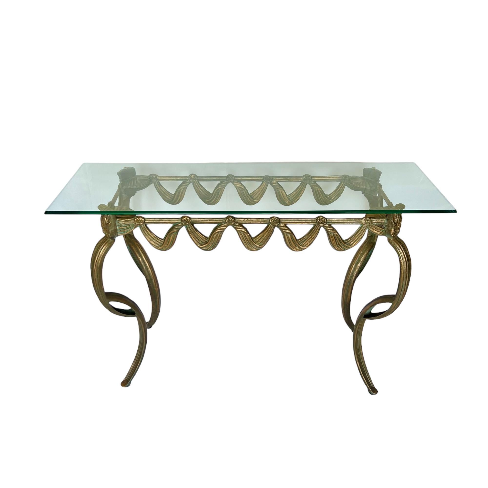 Antique gold and verdigris finishes accentuate the neoclassical design of this gorgeous console, highlighting its swag scalloped edge with rosette detail and long exaggerated cabriole legs. It has a beveled rectangular glass top surface of