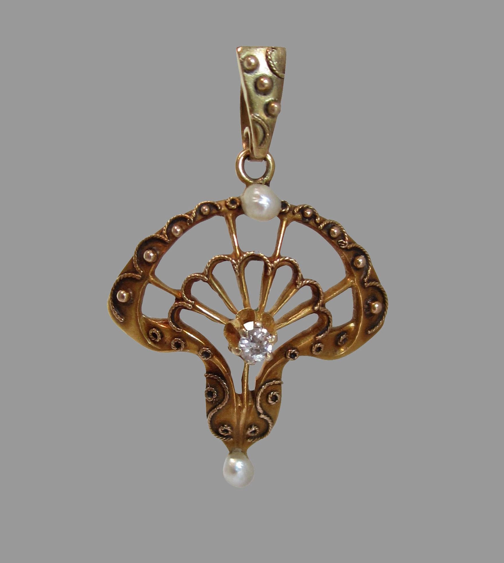 Designed as an openwork gold shell enhanced with raised scrolls, set with a small diamond and two pearls, with a matching gold suspension ring.

1890s

1 1/8 in. (2.8 cm.) long, including ring. Chain not included. 
