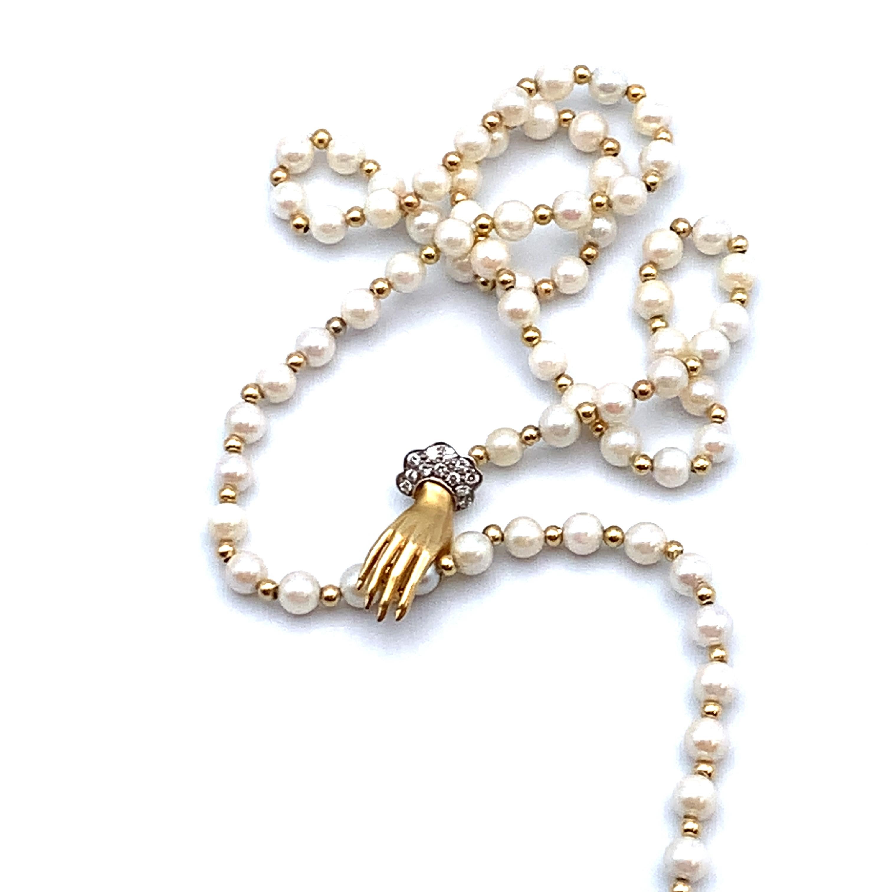 Lariat necklace set with alternating pearls and gold beads.  It fastens with a well-defined figural 