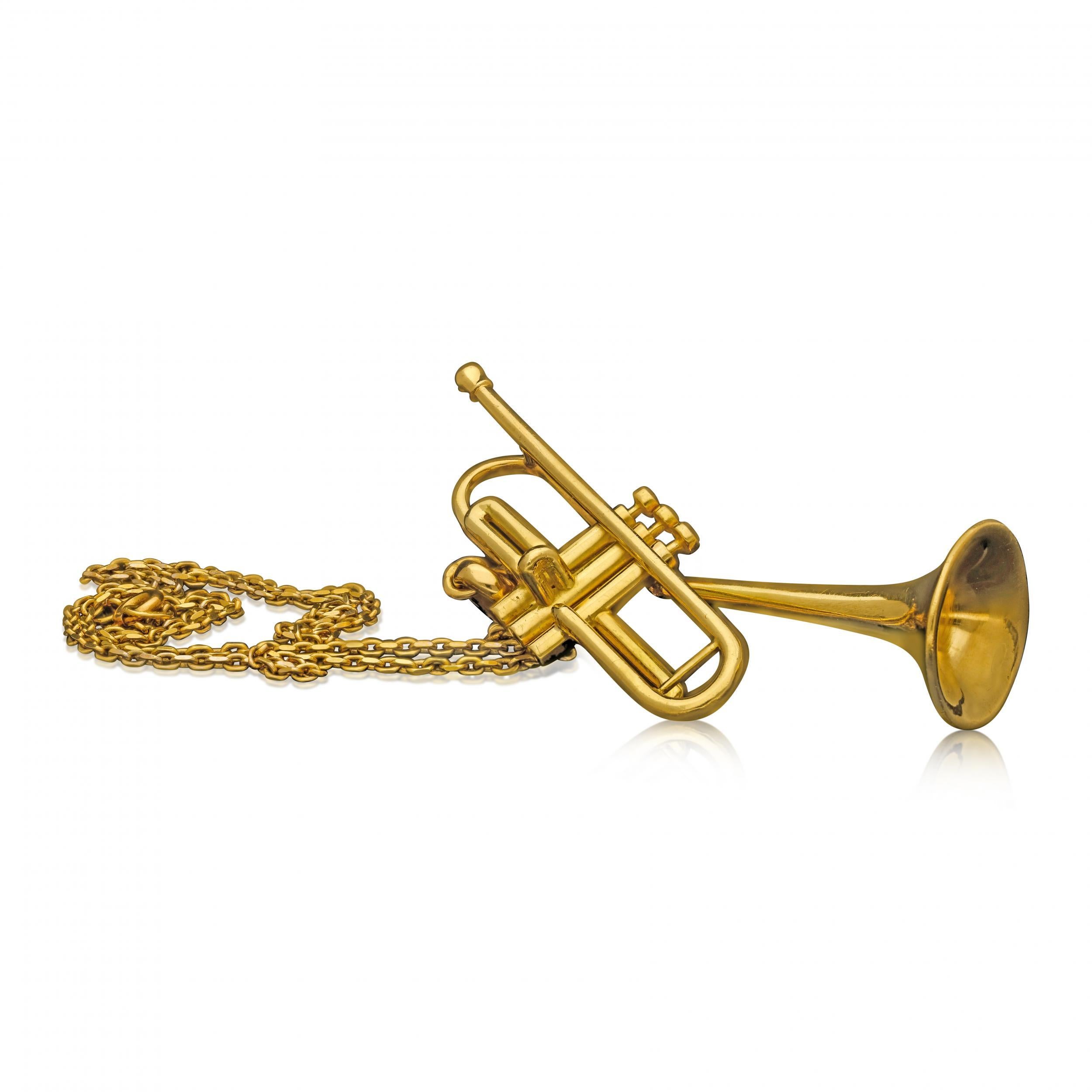 A gold pendant in the form of jazz legend Dizzy Gillespie's iconic 'bent' trumpet by Cartier c.1960s, the pendant realistically modelled in 18ct yellow gold and featuring the bell of the trumpet turned upwards at a 45 degree angle, originally the