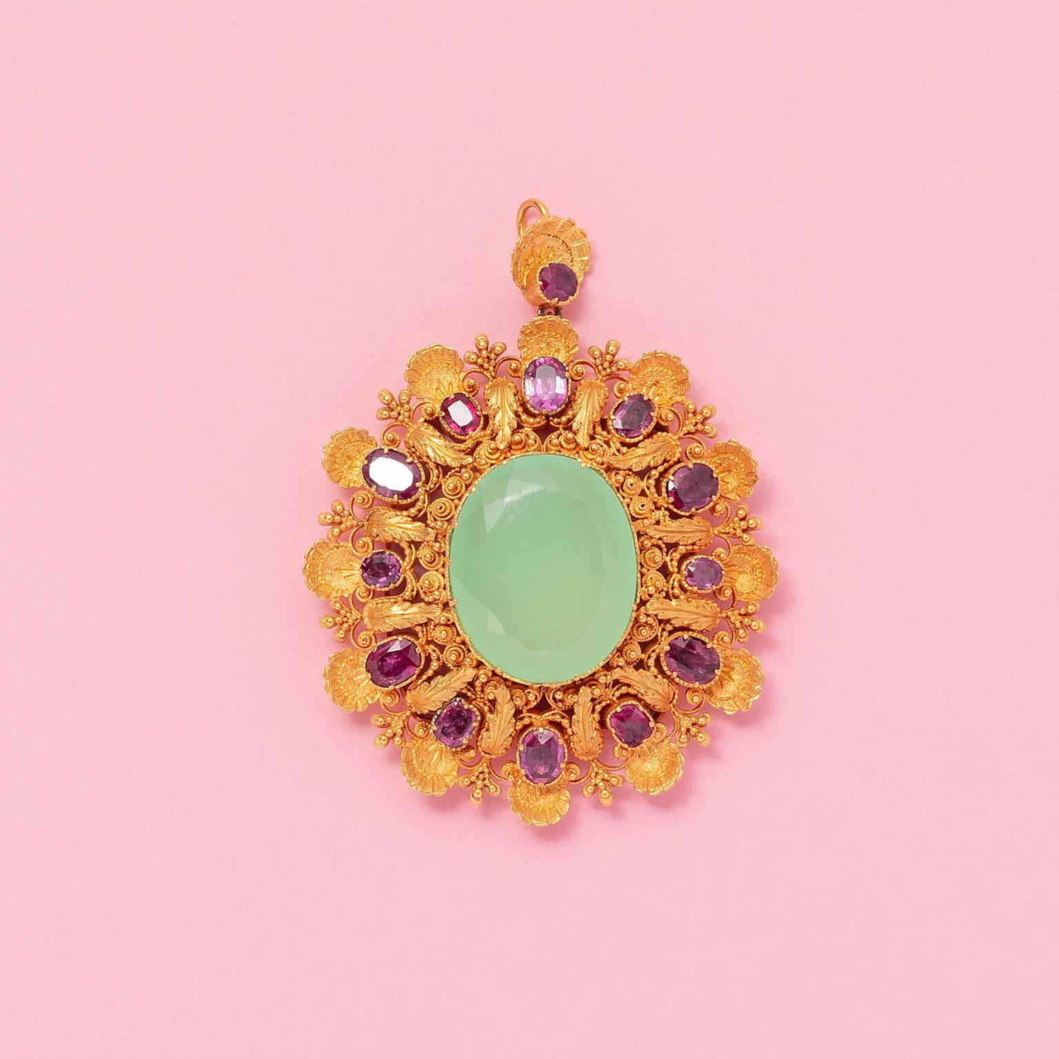A large 18 carat yellow gold, oval flower shaped pendant set with a large oval-facetted chrysophrase. surrounded by twelve oval-facetted pink-red rubies, alternating small and bigger. All richly decorated with filigrain, grains, gold leaves and gold