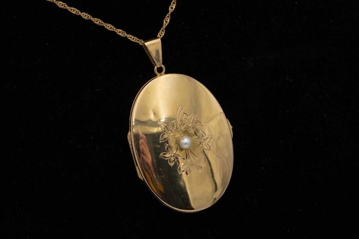 Gold medallion with a pearl - made of 0.750 yellow gold

A golden secretary with space for a photo of a loved one

Origin: Scandinavia, 1930s-40s

Decorated with a delicate engraved floral motif and pearl

Weight: 12.8g

Dimensions: 4x3cm

Very good