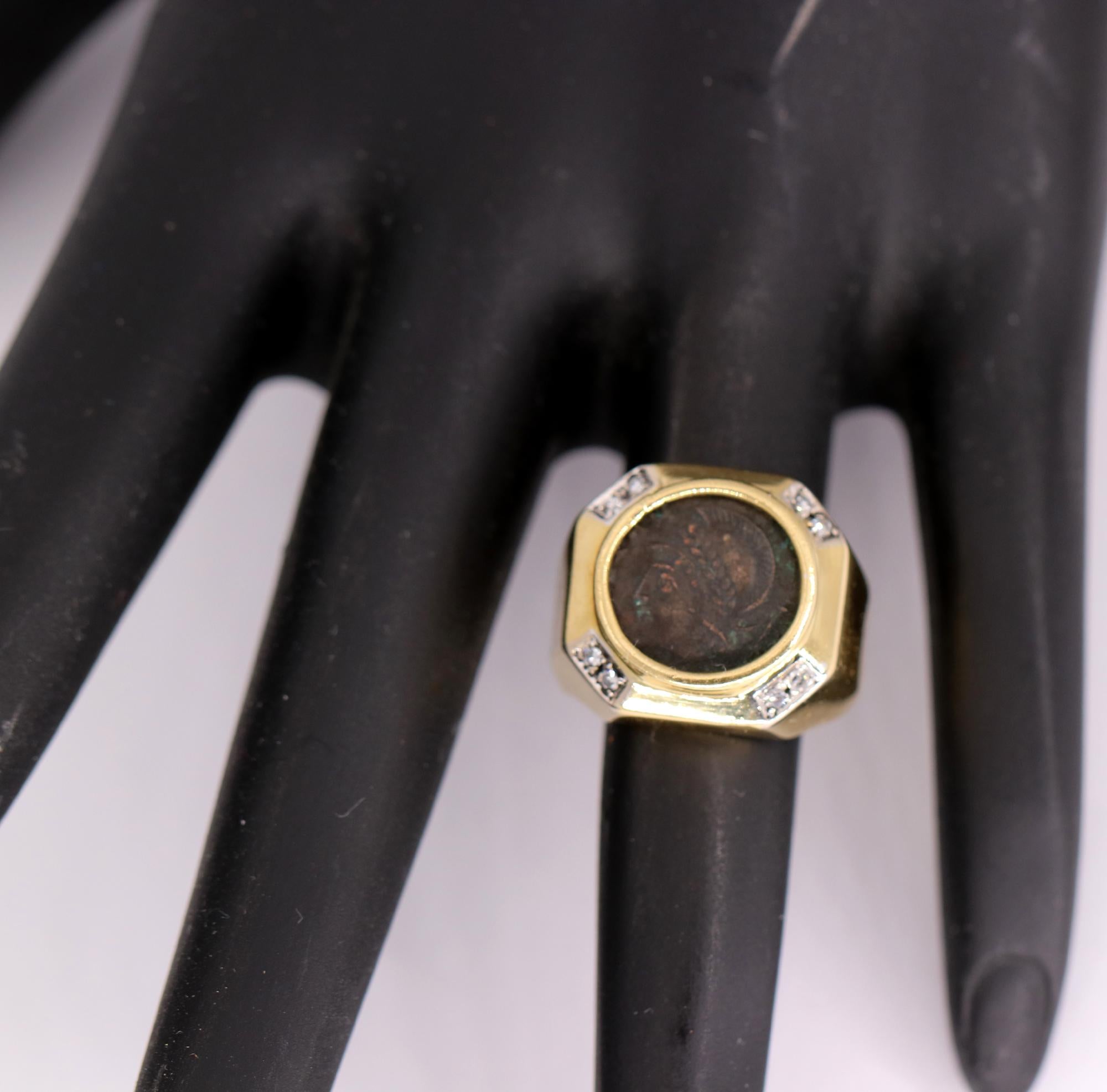 An 18 K yellow gold ring, with an octagonal outline, centered around an ancient coin. At each of the four corners, are set 2 single cut diamonds, adding a subtle sparkle. The ring is a diminutive size 4, making it an excellent pinky ring, and can be