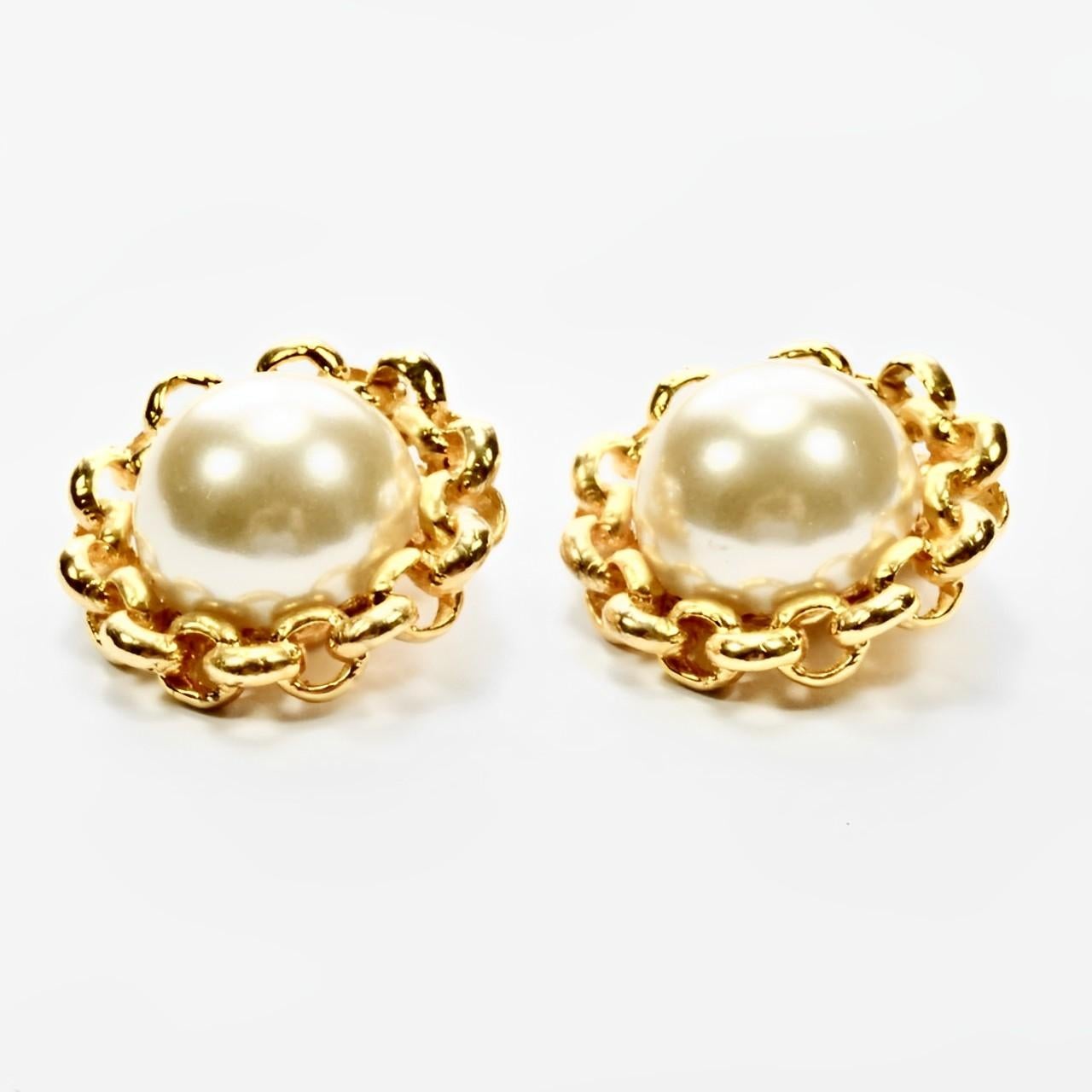 
Graziosi orecchini a clip placcati in oro con una perla finta a cupola e bordi a catena. Diametro di 2,8 cm / 1,1 pollici. Gli orecchini sono in ottime condizioni.

Questo è un meraviglioso paio di orecchini classici di perle finte. Circa anni '80.
