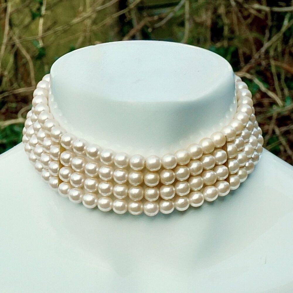 Maravilloso collar chapado en oro con cuatro hilos de perlas de imitación color crema, y una cadena de extensión. Las perlas están en tres secciones, con un diseño de cuerda y cierre de gancho.

Mide 31 cm de longitud con una extensión de 6 cm. La