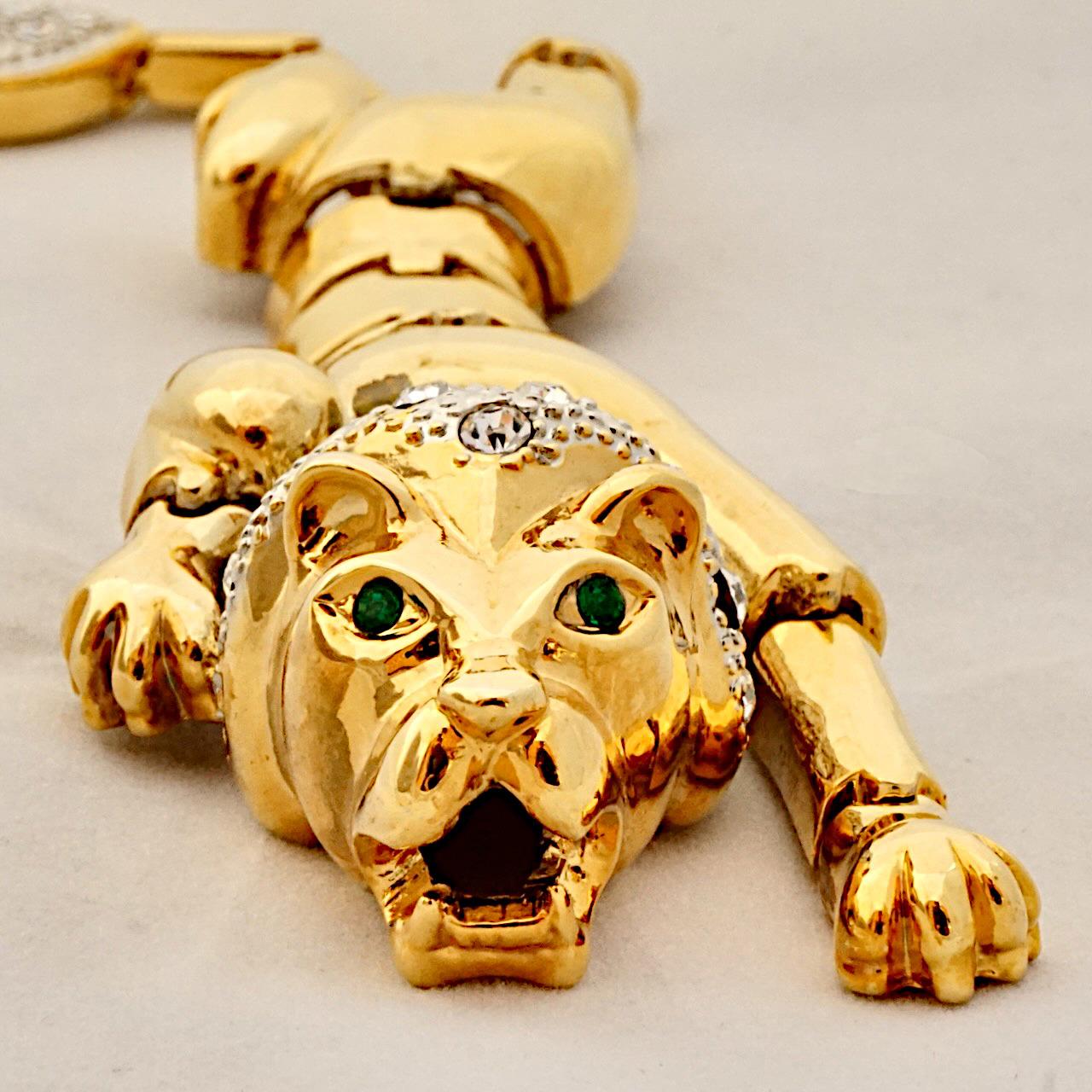 Gold plated articulated lion shoulder brooch, set with clear rhinestones, and two green rhinestones for the eyes. Measuring length 17.6 cm / 6.9 inches. The brooch is in very good condition, with some wear and scratching as expected.

This beautiful