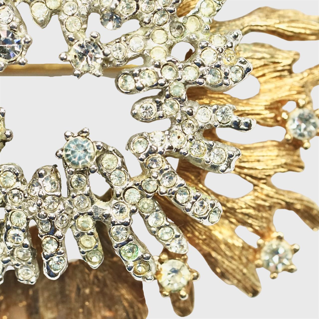 Fabuleuse broche en plaqué or et argent de haute qualité. La broche est composée de deux couches. La couche supérieure est plaquée argent et comporte une grappe centrale de strass, tandis que la couche inférieure est parsemée de strass sur une