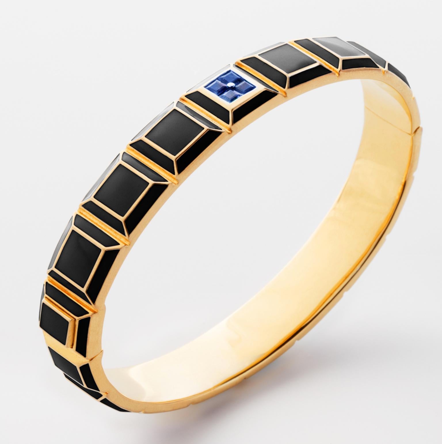 Gold-Plated Enamel Carousel Bracelet features a Yellow Gold Plated Silver bracelet with black enamel and blue sapphires, along with a clasp closure that secures the bracelet onto the wearer's wrist. 
Yellow Gold Plated Silver, Black Enamel, Blue