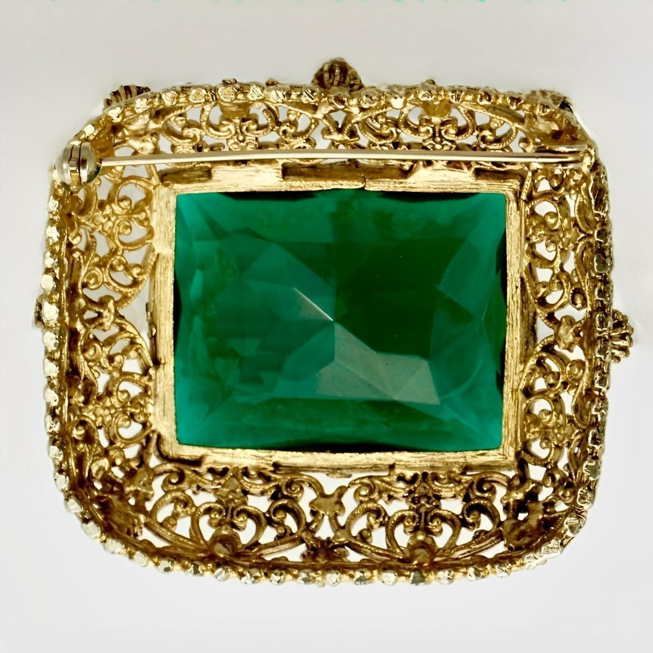 Gold plated filigree brooch featuring a large emerald green glass stone and eight green accent stones. Measuring length 5.4 cm / 2.1 inches by width 4.7 cm / 1.8 inch.

This is a beautiful and elegant statement brooch with emerald green glass