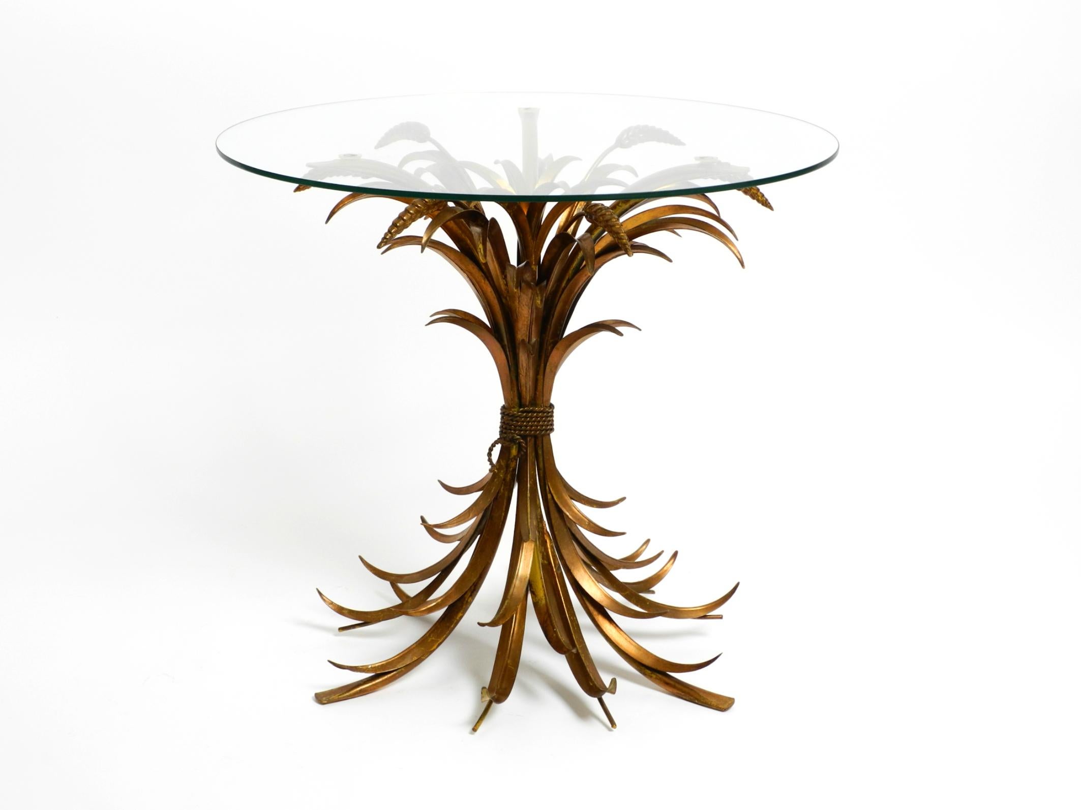 Beautiful 1960s rare gold-plated Florentine Regency side table or bedside table.
The classic among floral tables. Design and production by Hans Kögl.
The frame has three curved legs and many plant leaves with a thick round glass top.
Great design