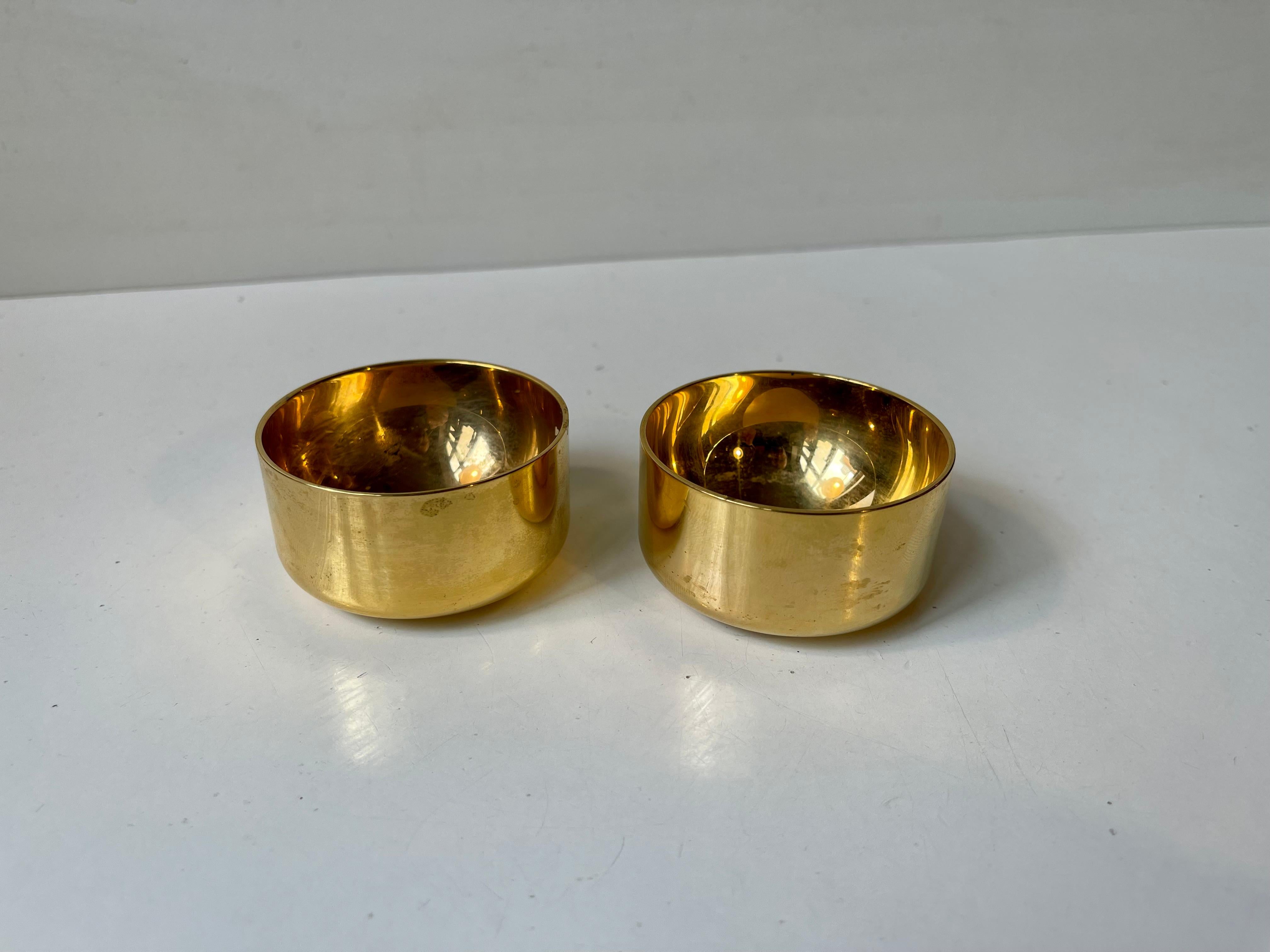 Originally designed as drinking cups/shot glasses these small beauties serve so well as tea light candleholders. They are made from gold plated metal and has a small blue unattributed emblem to one side. Designed by Pierre Forssell and made by