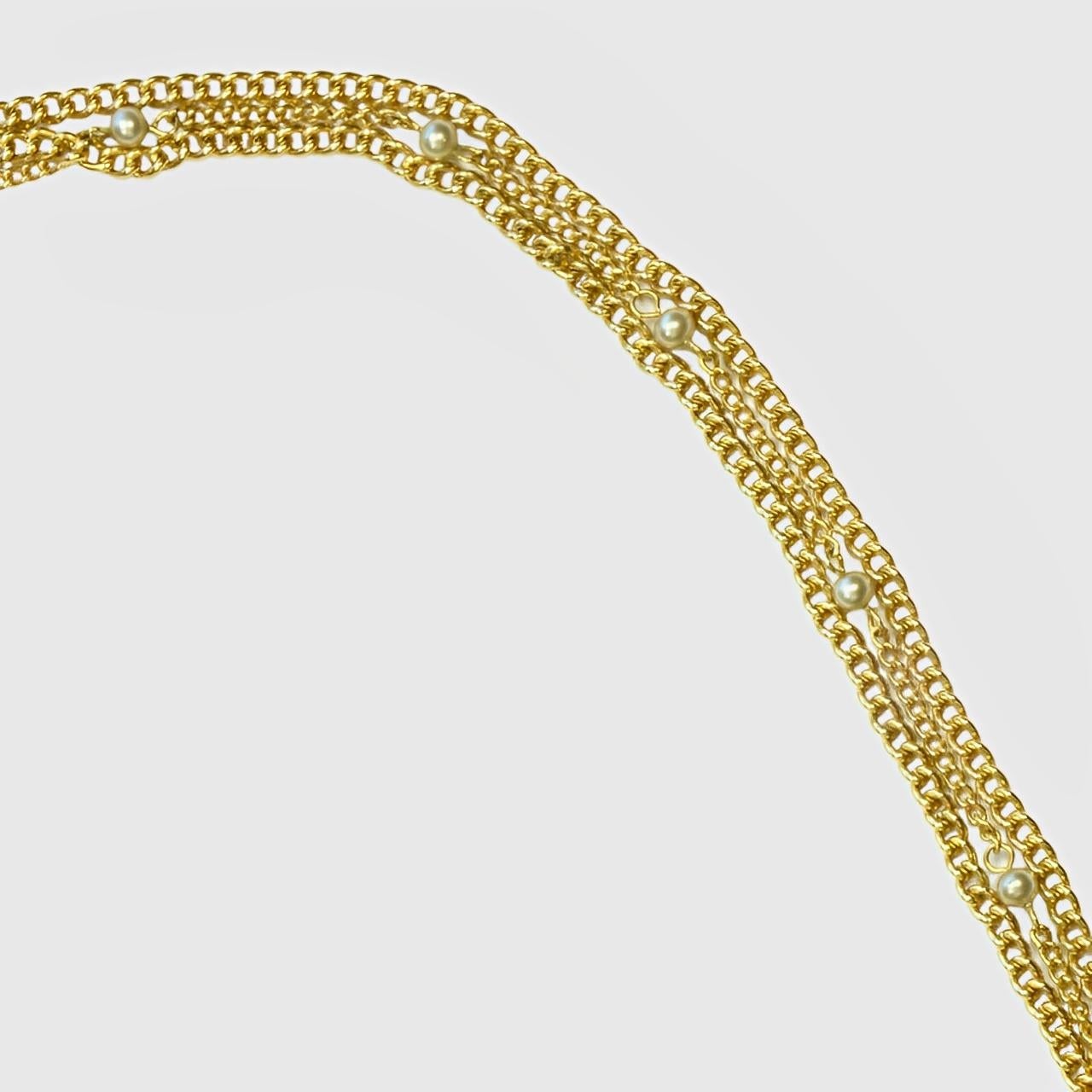 Precioso collar de cadena de tres vueltas chapado en oro. Dos de las tiras son lisas y una lleva perlas de imitación grises. Longitud 123 cm / 48,4 pulgadas. El baño de oro y las perlas de imitación están desgastados.

Este collar clásico es de la