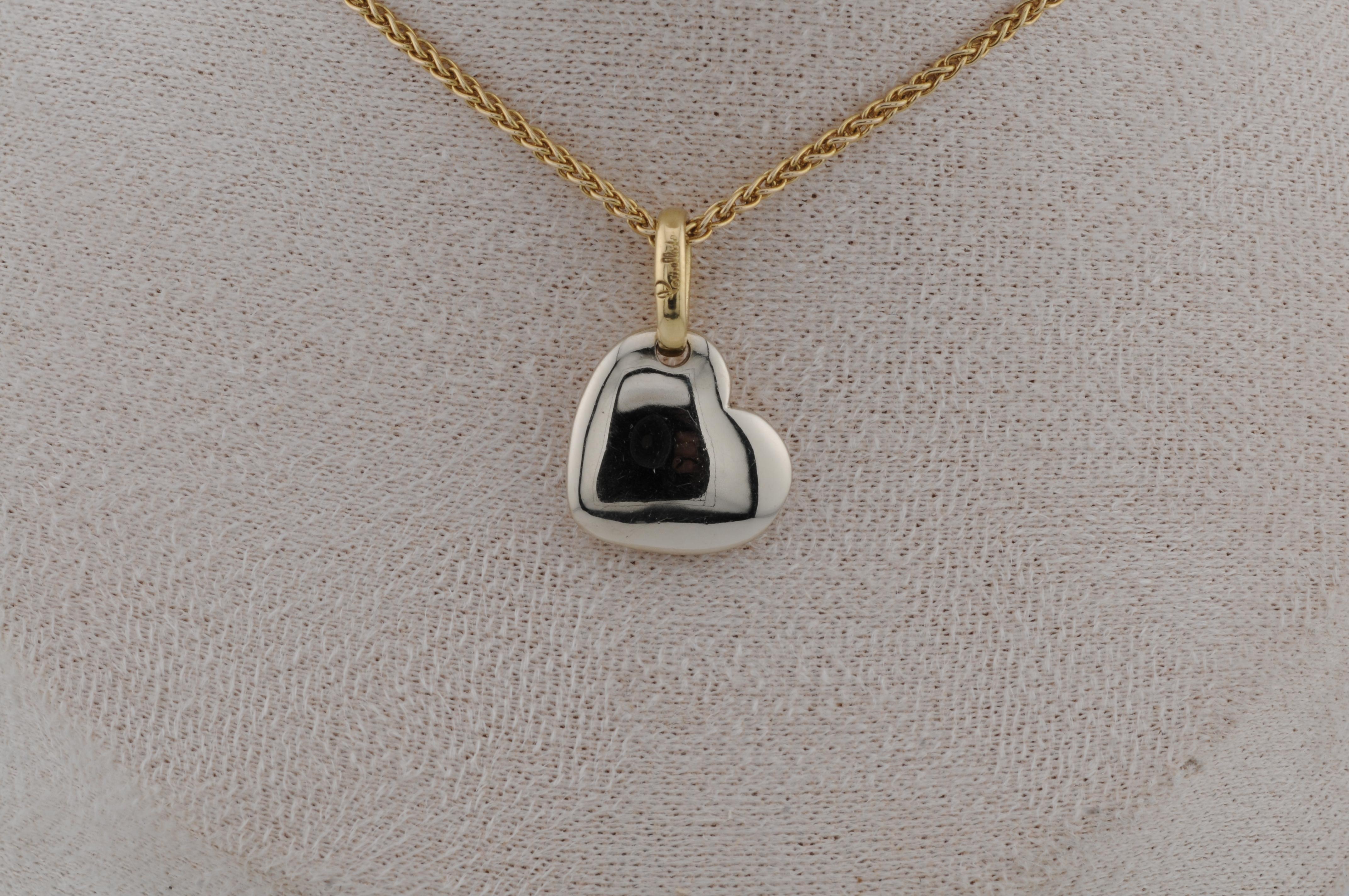Ciondolo in oro bianco 18 carati di Pomellato, a forma di cuore. Il design è pulito e sobrio, con una superficie lucida che evidenzia la qualità del materiale. La forma morbidamente arrotondata riflette l'estetica tipica del marchio. Il ciondolo è