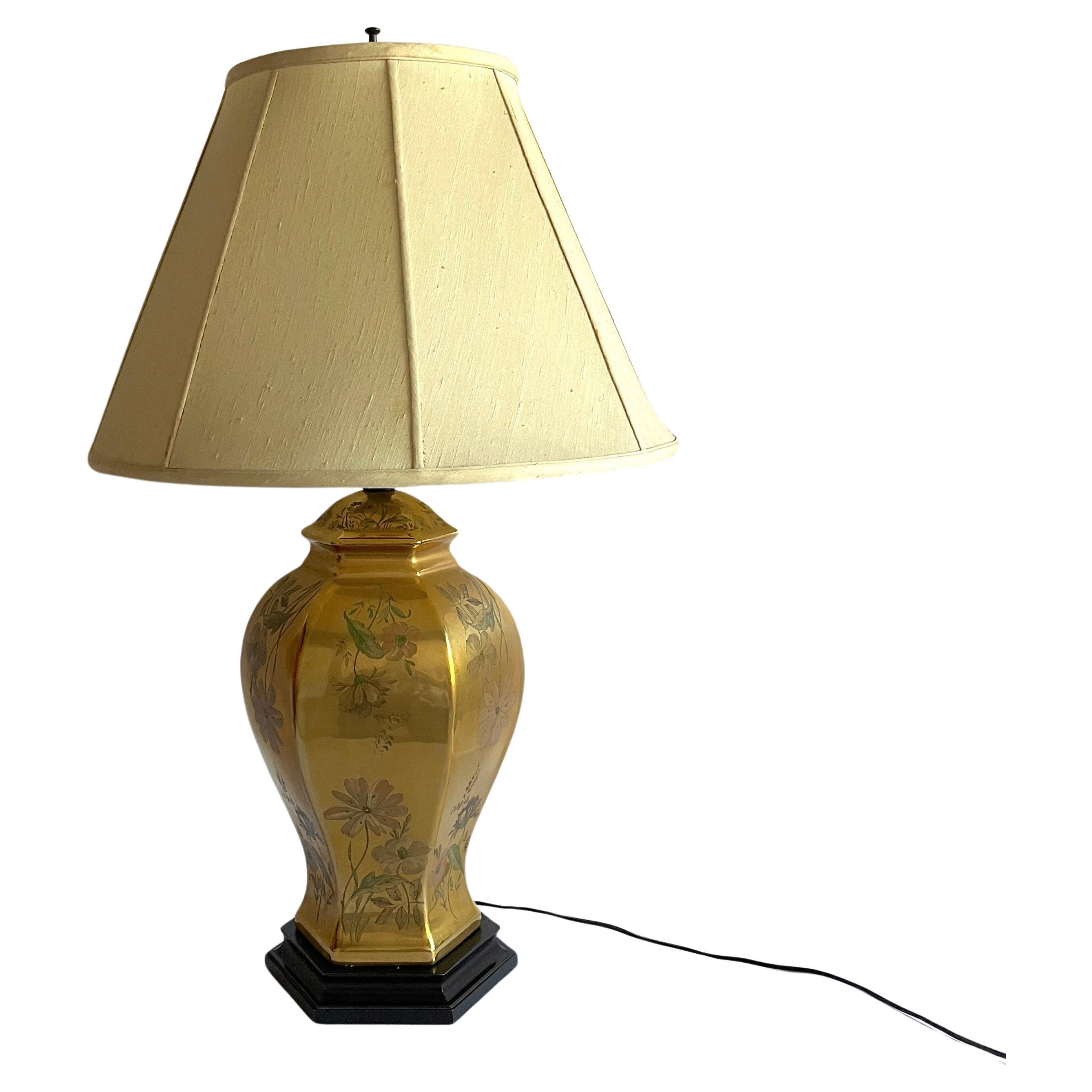 Exceptional table lamp made of gold color porcelain hand-painted with floral and vines motifs mounted on a solid wood base. A beautiful object of art for display. Includes original off-white (with a slight chartreuse-y green tint) and finial -- but