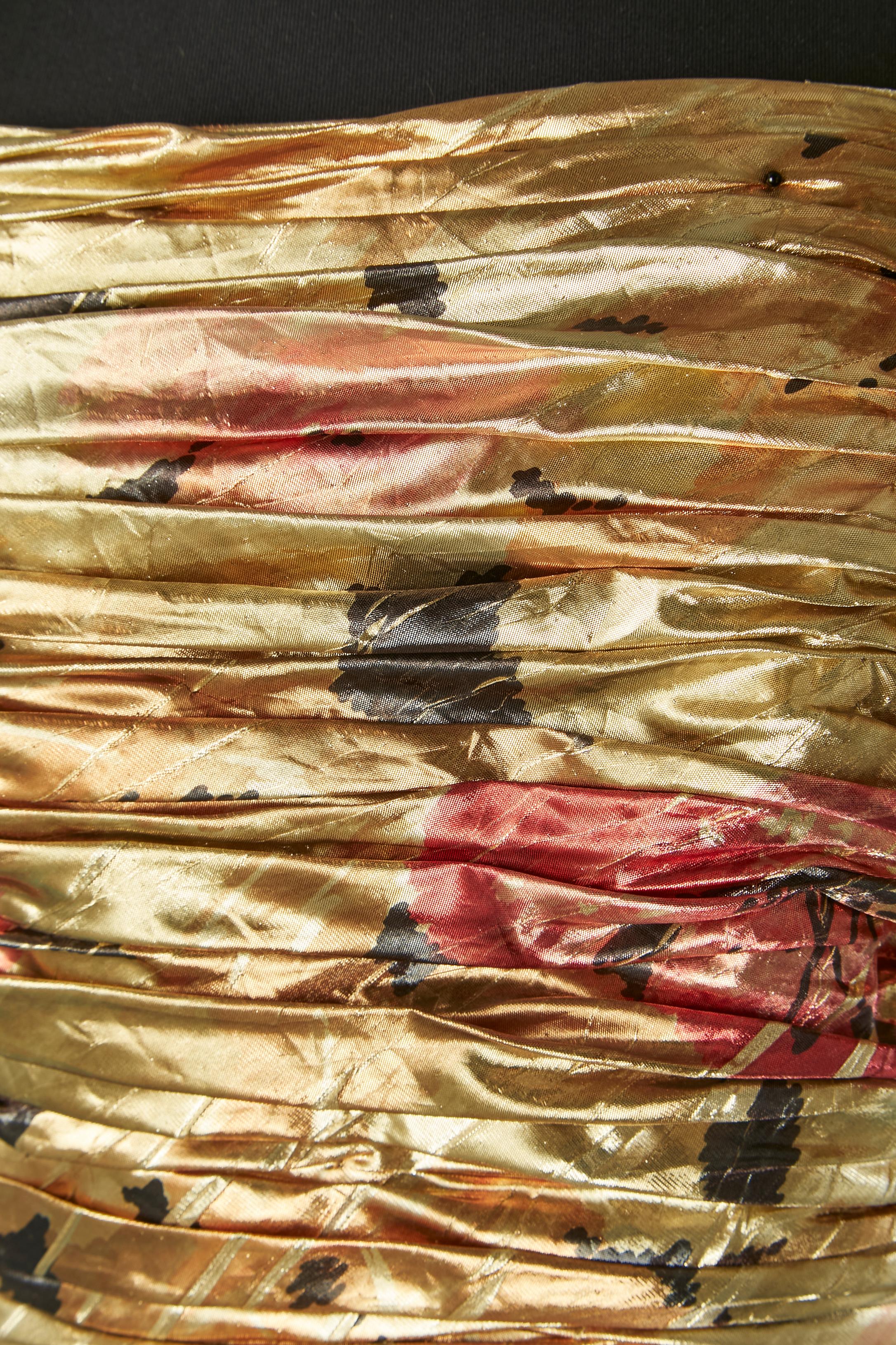 Abito da sera drappeggiato in lamé stampato oro. Non c'è l'etichetta della composizione del tessuto, ma la fodera è probabilmente in rayon e la seconda fodera in morbido tulle. Fiocco sulla spalla. Drappeggiato sul busto e raccolto. Disossato.