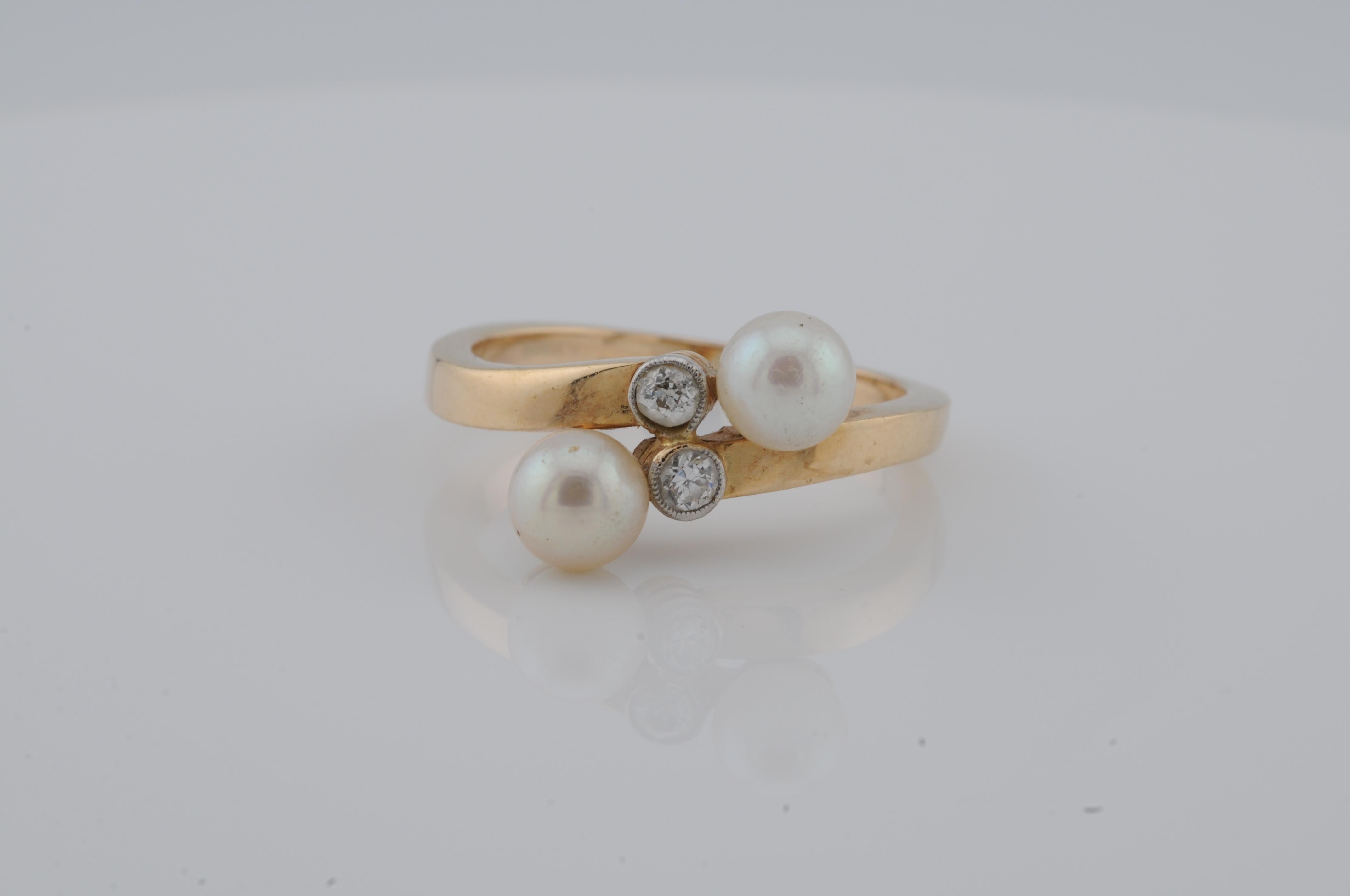 Anello in oro giallo 14K, realizzato in stile Art Deco.

Con due perle naturali e due diamanti taglio vecchio, peso totale circa 0,10 ct. L'incastonatura è discreta, con una disposizione simmetrica delle pietre.

Il design riflette la chiarezza