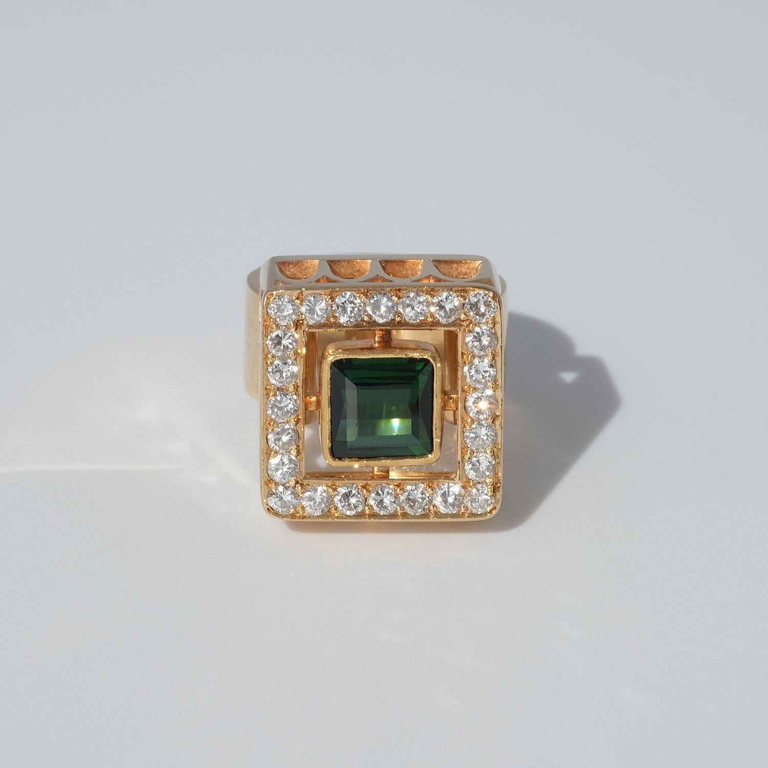 This 18 karat gold ring has a tourmaline and 24 brilliant cut diamonds. The ring's head is square shaped with a pattern that looks like the window-frames of an ancient English Gothic cathedral. 

The ring radiates powerfulness and self-confidence