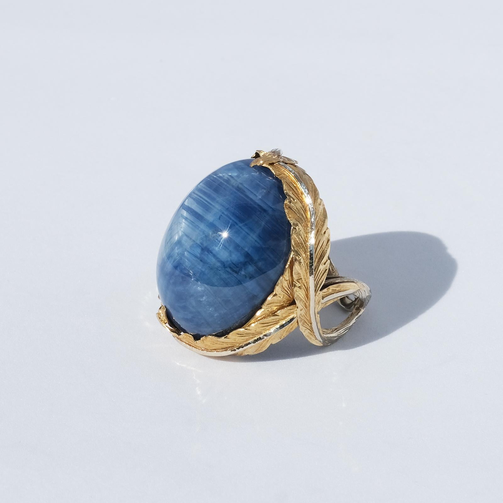 Designer: Kristina Karlsson (d. year 2000)

Year: 1990s

This amazing very large gold and partly silvered ring has a large cabochon polished sapphire and a setting which is adorned with a beautiful golden laurel wreath. The ring looks like a
